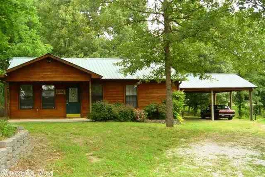 CABIN HOME with modern comfort in a pretty area close to town.  The  home has a comfortable living room with gas log fireplace.  A pretty kitchen features nice cabinets & all appliances are included. The roomy bath has good storage, a laundry area that includes the washer and dryer. Some of the features are a tank-less water heater, laminate & tile flooring, metal roof, heat pump, covered front porch, covered patio off the kitchen, 2 car carport & pretty yard.  Possible owner will carry 2nd. ONLY $130,000