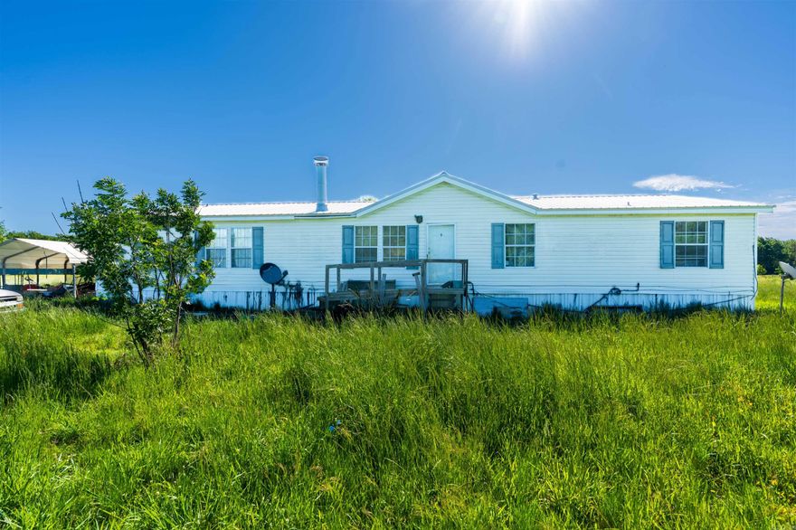 Discover the potential of this country property situated on over an acre of open land, offering privacy, space, and endless opportunities. This manufactured home features a spacious layout with multiple living areas, a large kitchen, and generous bedroom sizes. The property includes an additional covered structure and plenty of outdoor space for storage, gardening, recreational use, or future improvements.  The home will require repairs and updates throughout, making it an ideal investment opportunity or project for buyers looking to customize a property to their needs. With its wide-open surroundings and rural setting, this property offers a peaceful lifestyle with room to grow.  Whether you're seeking acreage, value, or a renovation project, this property provides the foundation to create something truly your own.