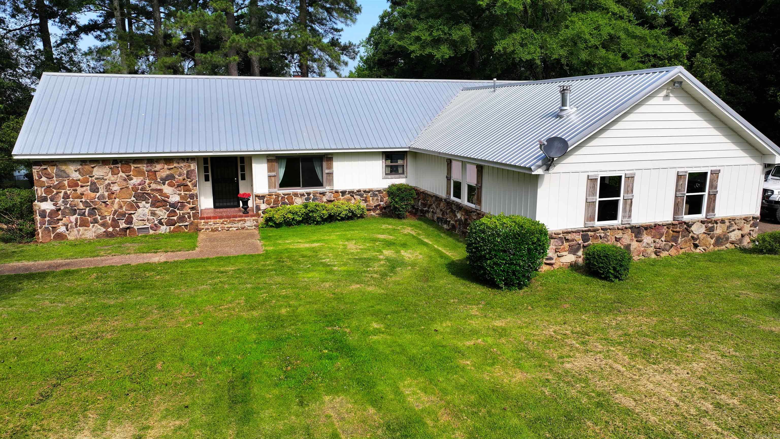 Nestled on 5 beautiful acres, this spacious 3- bedroom, 3- bath home offers the perfect blend of comfort, privacy, and natural beauty. Ideal for those seeking peace and room to roam, this property features a picturesque private pond, perfect for fishing, relaxing, or simply enjoying the view from your backyard. Inside you will find gorgeous hickory wood floors, a large living room with vaulted ceilings, and a beautiful rock fireplace. The kitchen includes updated appliances, a copper sink, and ample cabinet space. Each bedroom is generously sized, with the primary suite featuring a private bath with his and her sinks. Additional highlights include a second living space with a built in jacuzzi hot tub, and a screened in patio over looking the pond. This property also includes 2 versitile shops, a larger shop for vehicles or room to work, and a smaller shops great for storage. There is also a screened in gazebo with a nice seating area. Whether you are looking for your next hunting lodge or your dream home, this house has everything to offer.