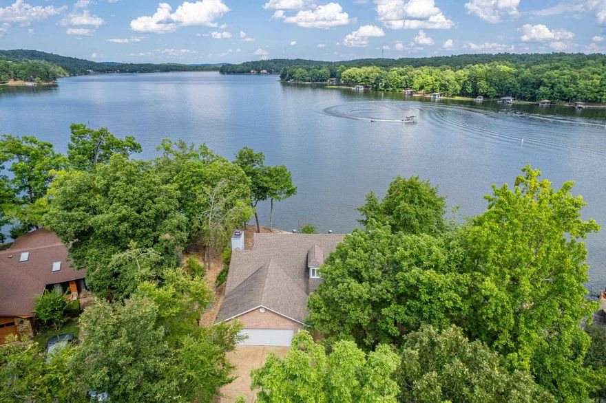 WHAT A VIEW! Lakefront living, custom designed with living LARGE in mind! Amazing design for entertaining, crafting, working from home, and just sitting in the Arkansas room gazing at the lake in all directions! The spacious open, vaulted living dining area welcomes you with a custom serving island and storage for days! The Arkansas room calls you through to enjoy the view, playing games, or heading down to the Covered dock with swim deck! You'll love the spacious concrete area leading to the water for putting kayaks in or setting up tables for a special event, additional patio set or a fire pit! The kitchen cabinets are custom and create a warm tone. The breakfast area boast more lake views and can hold a large table or could serve as a delightful sitting area! The spacious pantry/ laundry room combo is conveniently designed! The main bedroom features dual bathrooms and dual closets! Don't miss the "corner office with a view" which could be used as a 5th bedroom if needed! Down stairs features 3 more bedrooms! (one currently used as an office) There's a den, LARGE storage room, full bath and access to the WAY over-sized workshop area (not included in sq ft!!) NEW ROOF 7/24!