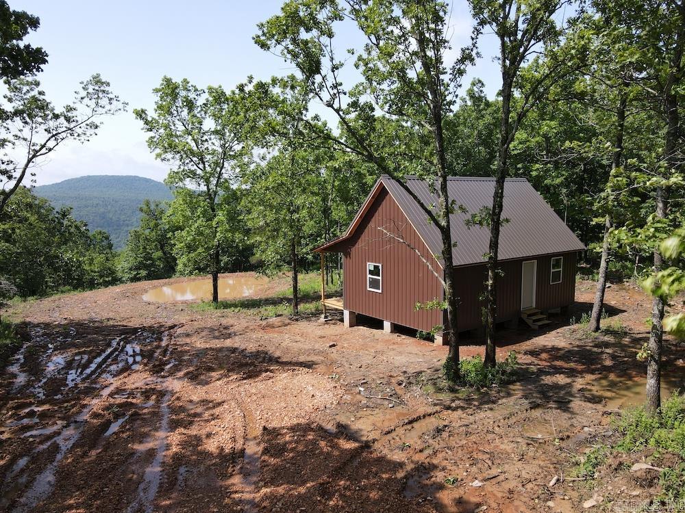 Check out this incredible gem in the heart of the Ozark Mountains, just minutes from Marshall, AR and the renowned Buffalo National River. Ideal for hunters, outdoor enthusiasts, or anyone seeking a private getaway, this tract lays atop the mountain with gentle, level topography, making most of the acreage usable. The land is covered in mature hardwoods—Post Oak, Red Oak, White Oak, Hickory, and more. A newly constructed metal-sided cabin with a metal roof sits among the trees, offering breathtaking views of the valley and mountains. A pond has been built just below the cabin. The structure includes a covered front porch, open living area, and a spacious loft for bedrooms, offices, or storage. It’s framed and ready for your personal finishing touch. Electric is nearby and easily accessible. The property also features small bluffs, rock outcroppings, and is home to abundant wildlife including deer, turkey, black bear, and even elk. With close proximity to National Forest and the Buffalo River, this property offers excellent potential as a vacation home or short-term rental. Don’t miss out—call today!