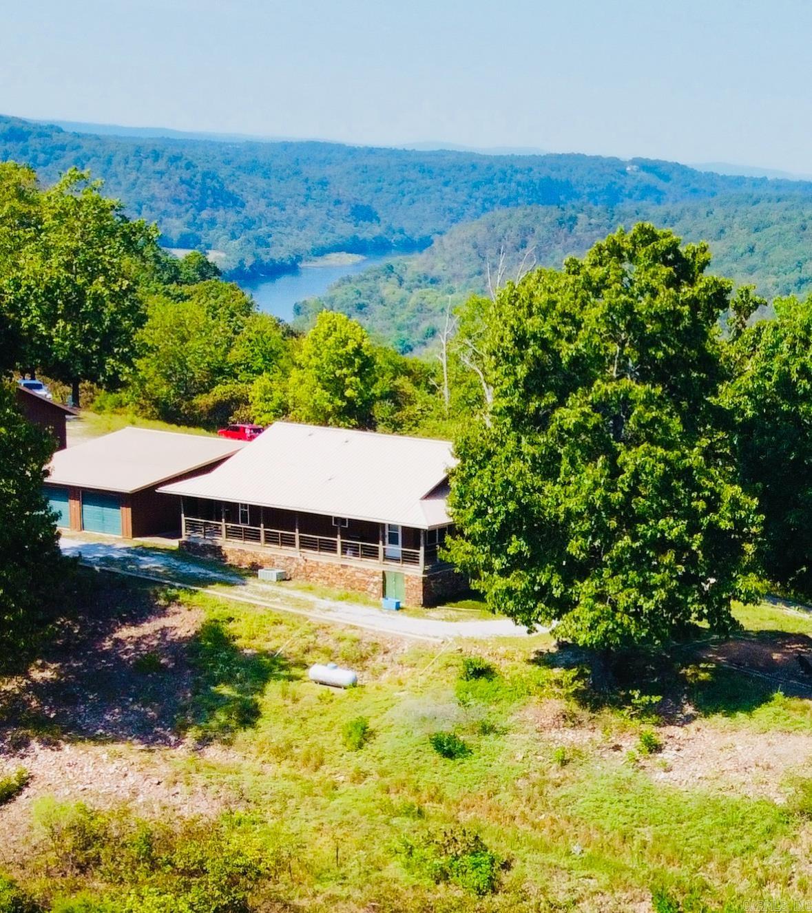 Million-dollar view!!! Prepare to be completely captivated by a view worthy of being chosen as a cover photo to represent the mountainous beauty of world-renowned Mountain View! The panoramic views from this gorgeous 10+ acre mountaintop property stretch across mountains, valleys, & the glistening White River below! Large windows in the well-maintained cabin frame magnificent views with a spacious open concept design, blend of farmhouse & rustic charm, & the timeless warmth of rich wood walls & flooring. Start your days on the covered wraparound porch as the morning mist rises from the river & enjoy relaxing evenings watching bursts of orange across the sky & water as the sun sets over the valley below. One detached garage has 4 garage doors with plenty of space for a workshop, home office, collectables, etc. A second detached garage has been uniquely converted into living quarters perfect for guests, in-law quarters, or for use as a nightly rental with a bedroom, full bath, & large kitchen/living combo plus a spacious loft to be finished for additional living space if needed. Beautiful, move-in ready, less than 2 miles to launch your boat for White River fishing, priced to sell!