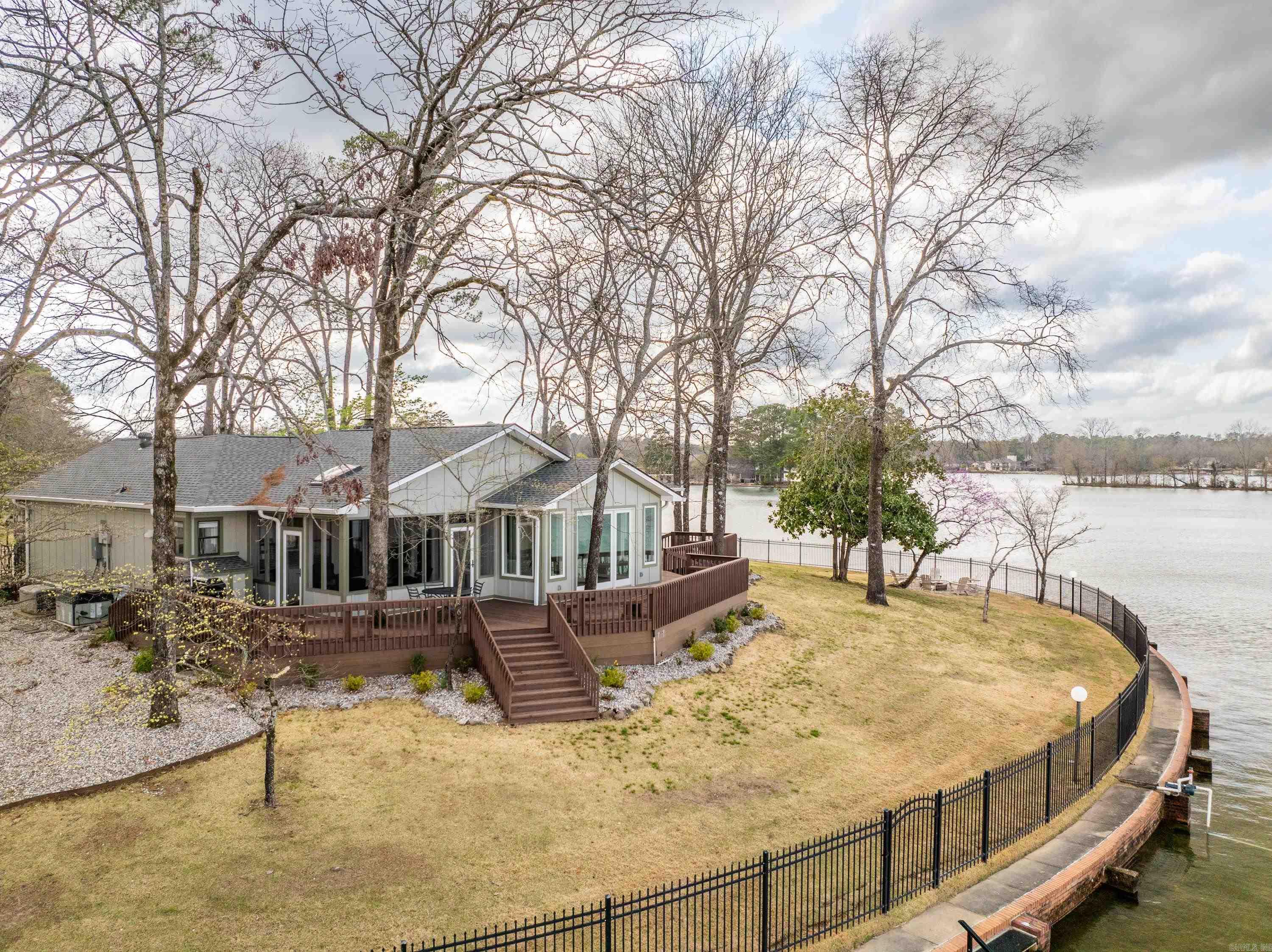 Nested behind gated elegance, this lakefront sanctuary on Lake Hamilton beckons with 317 feet of rare waterfront bliss. Immerse yourself in the feeling of a private island retreat as you explore the completely remodeled interior and exterior of this exclusive estate. A charming guest house awaits, while outdoor amenities such as an outdoor shower, a cozy fire pit, and a screened in porch enhance the lakeside lifestyle. Multiple outdoor spaces offer panoramic main channel views, ensuring each moment is a picturesque escape. Sold fully furnished, this is a turnkey opportunity to experience unparalleled luxury on the shores of gorgeous Lake Hamilton. Welcome to your lakeside haven.