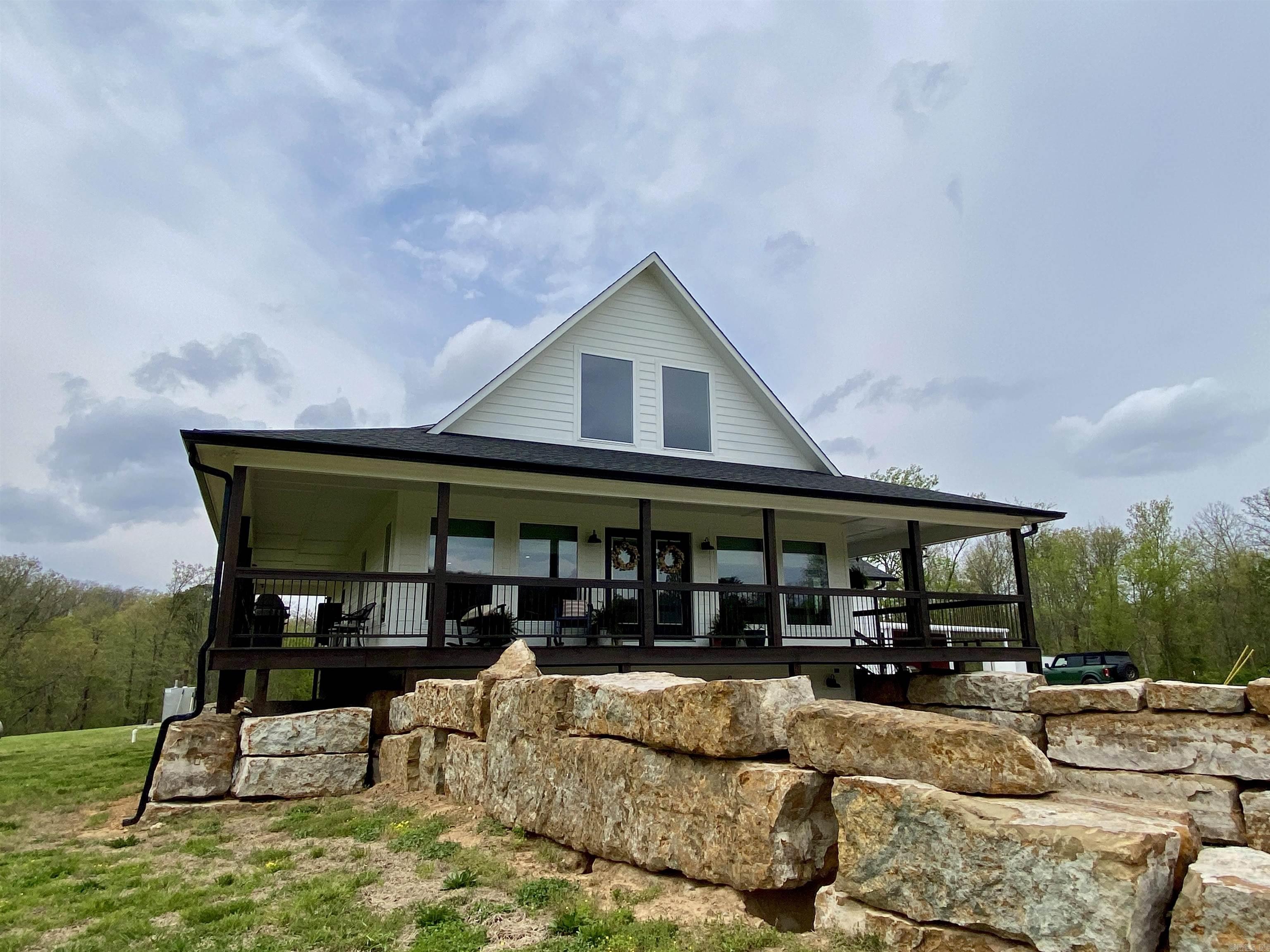 Fifteen serene acres in the heart of the Ozarks surround this stunning custom-built home, perfectly positioned to overlook rolling meadows and distant mountain views. Convenient to Clarksville yet completely private with no visible neighbors, the property offers peaceful seclusion without sacrificing accessibility. Inside, soaring vaulted wood ceilings and walls of windows frame the natural beauty and fill the open-concept kitchen, living, and dining spaces with light. The chef’s kitchen features custom cabinetry, granite countertops, a pantry, and stainless steel appliances. The walk-out basement adds versatility with a cozy den, workout or game area, office or 5th bedroom, safe room, workshop/craft space, and generous storage. The private primary suite includes direct access to the wraparound deck and a luxurious bath. Just steps away, a 36x50 heated and cooled shop includes a kitchenette, full bath, and lean-tos for equipment or ATVs. With the Ozark National Forest just minutes away, this property is the ultimate home base for everyday adventure.