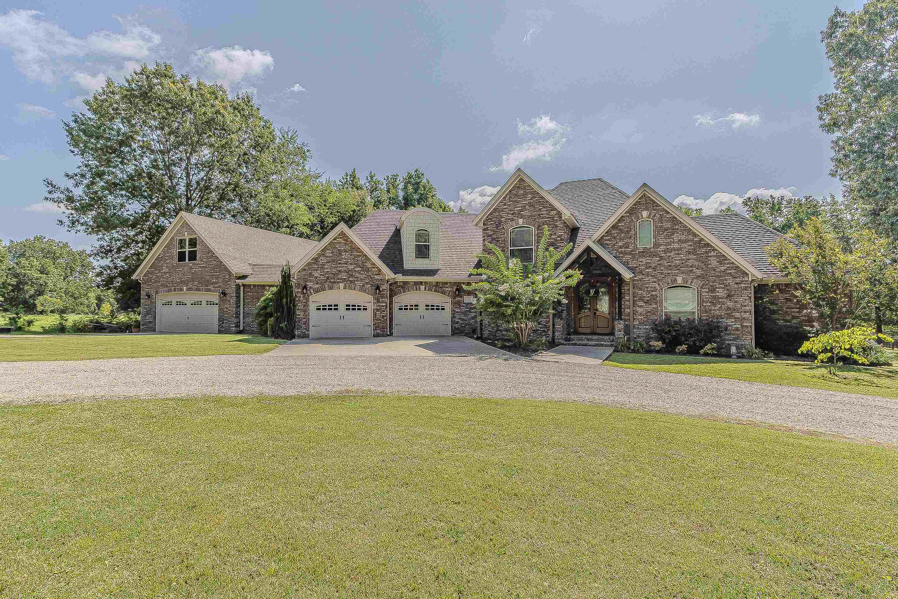From the moment you walk through the arched double iron doors, this all-brick home on 1.08 acres makes a statement. Inside, soaring 17’ vaulted ceilings, hardwood floors, and natural lighting bring warmth and grandeur to the living space, anchored by a beautiful fireplace. The kitchen is a standout with granite countertops, rich wood cabinetry, black stainless appliances, double oven, oversized island, and a walk-in pantry. Right off the kitchen, the walk-in laundry room doubles as an ultra-organized pantry—complete with custom shelving and cabinetry. The primary suite offers a peaceful retreat with a tray ceiling, spa-like bath featuring a jetted soaker tub under a chandelier, walk-in shower, dual vanities, and a spacious walk-in closet. Upstairs includes two bedrooms, a full bath, and a versatile loft—each room with its own walk-in closet. Enjoy outdoor living on the composite deck with pergola or the covered back porch. The heated and cooled 26x50 attached shop includes a finished bonus room—perfect for hobbies, business, or storage. Refrigerator, washer, and dryer stay—just move in and enjoy!