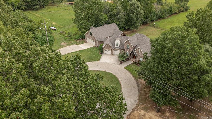 From the moment you walk through the arched double iron doors, this all-brick home on 1.08 acres makes a statement. Inside, soaring 17’ vaulted ceilings, hardwood floors, and natural lighting bring warmth and grandeur to the living space, anchored by a beautiful fireplace. The kitchen is a standout with granite countertops, rich wood cabinetry, black stainless appliances, double oven, oversized island, and a walk-in pantry. Right off the kitchen, the walk-in laundry room doubles as an ultra-organized pantry—complete with custom shelving and cabinetry. The primary suite offers a peaceful retreat with a tray ceiling, spa-like bath featuring a jetted soaker tub under a chandelier, walk-in shower, dual vanities, and a spacious walk-in closet. Upstairs includes two bedrooms, a full bath, and a versatile loft—each room with its own walk-in closet. Enjoy outdoor living on the composite deck with pergola or the covered back porch. The heated and cooled 26x50 attached shop includes a finished bonus room—perfect for hobbies, business, or storage. Refrigerator, washer, and dryer stay—just move in and enjoy! This property is priced below appraisal and seller is offering $10,000 in concessions.