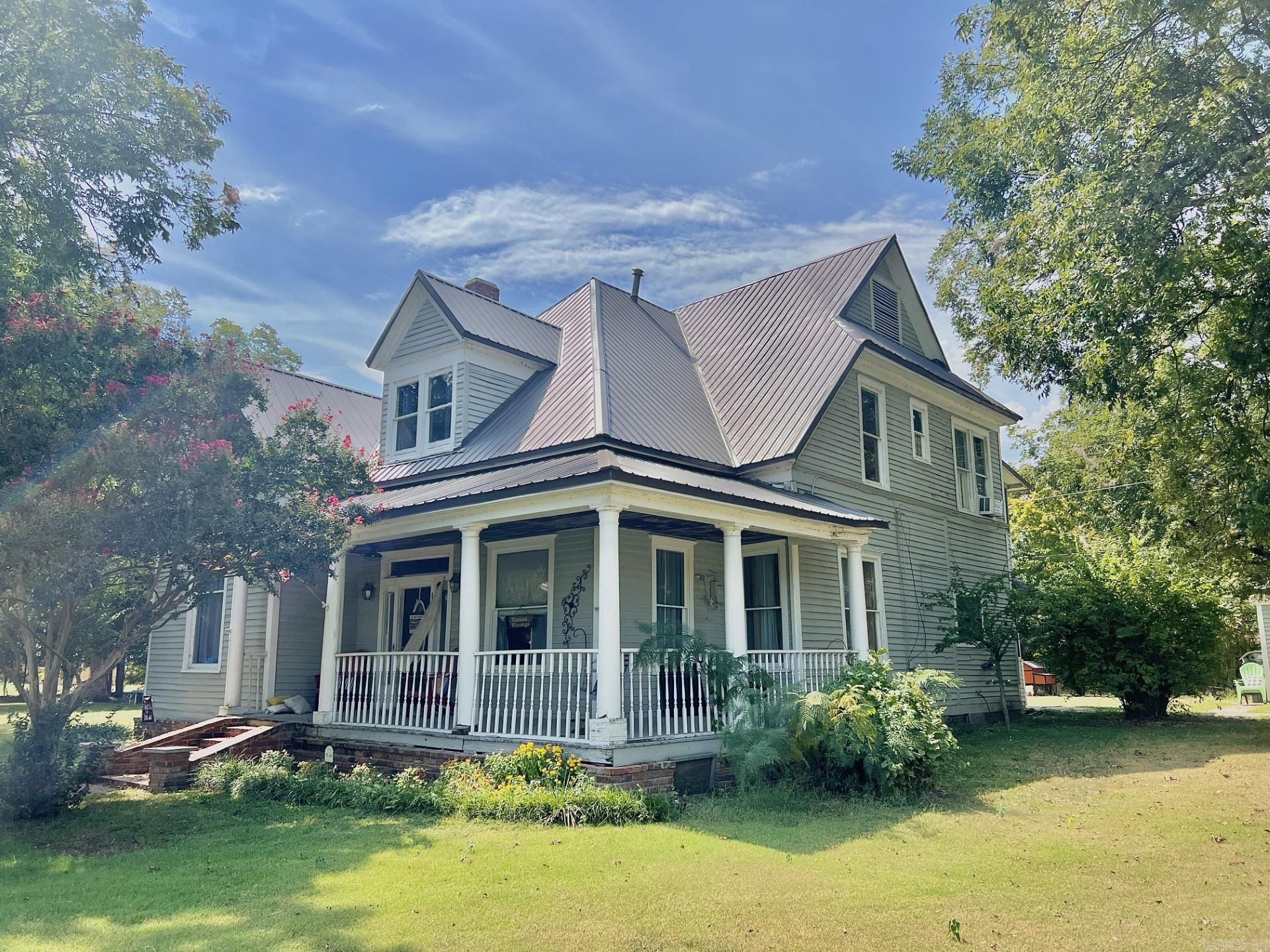 Step back in time with this stunning two-story 1912 home in Tuckerman, AR, offering 3,434 sq. ft. of living space with 5 bedrooms and 3 full bathrooms. From the welcoming foyer with its grand staircase and dining room to the right, to the spacious open living room that flows into the den, this home is full of charm and character. The kitchen features brick flooring, a stove/oven combo, and a breakfast bar that connects directly to the dining area, making it perfect for gatherings. Historic details like two decorative fireplaces (sealed but still adding personality), tall ceilings, and timeless design give this property its classic feel. Outdoors, enjoy a wraparound front porch, a screened-in back porch, and a screened balcony on the second level overlooking the .75-acre corner lot. A detached 2-car garage provides convenience, while the spacious layout and unique character make this home truly one of a kind.
