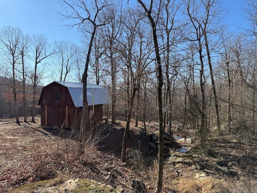 Tucked deep in the Ozarks, this private 10-acre tract in Searcy County near Snowball, Arkansas, offers the perfect escape for hunters, preppers, or anyone seeking seclusion and natural beauty. The mostly wooded land features gentle, rolling terrain with mature hardwoods,white and red oak, post oak, hickory, and maple, creating excellent habitat for deer, turkey, and other wildlife in an area known for strong whitetail genetics. A small cabin with a loft and covered porch sits overlooking the timbered landscape. Built with wood siding and a metal roof, it has an authentic Ozarks feel and is framed and partially wired inside, ready to be finished to your liking. A wood-burning stove adds cozy comfort for fall and winter stays. A scenic spring flows through large boulders just below the cabin, paired with mountain views that enhance the peaceful, remote setting. Despite the privacy, the property has good access and is just a short drive from the Buffalo National River, National Forest lands, and Marshall, AR. An adjoining tract with another cabin is also available for expansion.