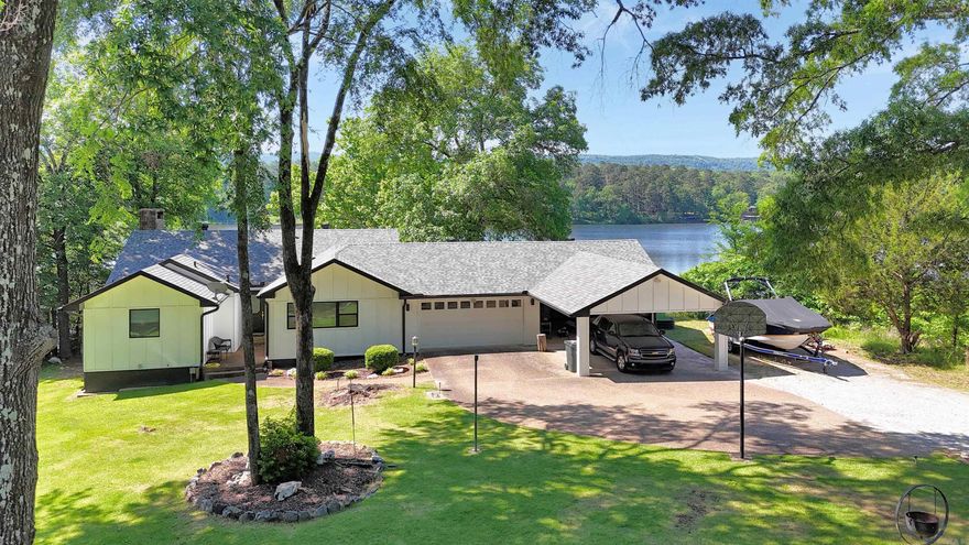 Welcome to your lakefront retreat! This beautifully maintained home has had only two proud owners, and it shows in every thoughtful upgrade throughout. Step inside to discover a main level designed for effortless living. The updated kitchen opens graciously into the dining and living areas, where abundant windows flood the space with natural light and frame those gorgeous lake and mountain views. The primary bedroom features a private en suite bath with large walk-in closet, while a guest bedroom, full bath, and convenient laundry round out the main floor. Head downstairs to find 2 add'l guest bedrooms, full bath, a dedicated office, and a second living area perfect for hosting guests. Outside features a patio and a tiered backyard with multiple decks that cascade down to 98' of lake frontage where you’ll find your covered boat dock, jet ski dock, and swim dock, making every summer day feel like a permanent vacation. Practical features include new Hardie panel siding, roof, and gutters all installed in 2023, a 2-car garage, and a 4-car carport for all your toys and vehicles. This home delivers the complete lakefront lifestyle package you've been looking for. Call today!
