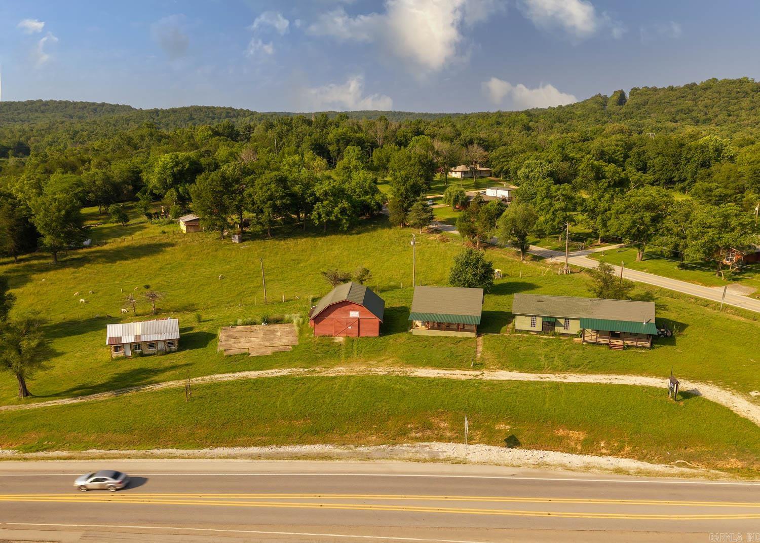 Unlock the potential of this rare commercial opportunity with prime frontage on busy Highway 63 in the Missouri Ozarks. This high-visibility property features four buildings and a 40x40 concrete pad across a generous layout with multiple access points—ideal for customers, guests, or deliveries. The 1,488 sq ft storefront offers versatile space for retail, office, studio, or showroom use with great roadside presence. Two of the buildings are well-suited for Airbnb rentals or residential conversion, providing on-site housing or extra income potential. A 36x34 barn with a concrete floor offers endless options—convert it into a workshop, event venue, retail space, or hobby barn. The concrete pad adds room for future development such as storage buildings or outdoor seating. With two wells (one active), this property offers flexibility for future expansion. Whether you’re launching a new business, creating a mixed-use setup, or investing in rental potential, this property delivers space, infrastructure, and prime location for success.