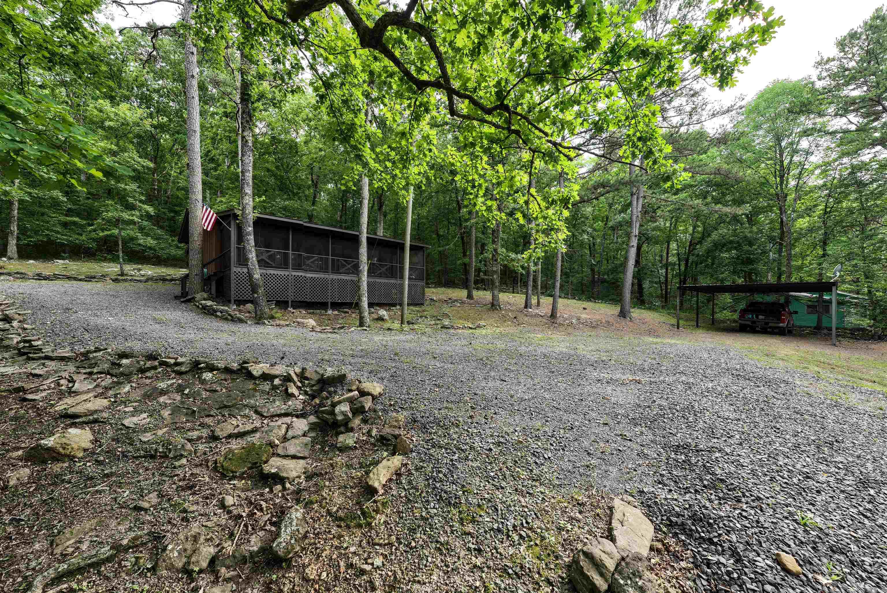 Imagine stepping into a fairy-tale retreat just moments away from the serene waters of Greers Ferry Lake. This charming cottage boasts an irresistible blend of quaint charm and modern comfort. Picture yourself lounging on a spacious screened porch, surrounded by the tranquility of nature. Inside, knotty pine hardwood floors exude warmth and character. Nestled on a private wooded acre, the property features a delightful cross bridge over a mini rock gully, adding a touch of whimsy to the natural landscape. Newer interior and exterior paint, along with a convenient metal carport covering for boat storage, every detail has been thoughtfully attended to. This adorable cottage offers a haven of relaxation and outdoor adventure, perfect for escaping the hustle and bustle of everyday life.