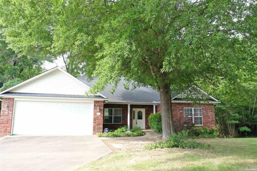 Discover the charm and convenience of this beautifully maintained one-level brick home, designed for comfort and easy living. Step inside to find gleaming hardwood floors, hard-surface countertops, and a welcoming layout that includes a formal dining room perfect for gatherings.  The spacious primary suite is a true retreat, offering his-and-hers walk-in closets and plenty of room to unwind. A cozy gas-log fireplace anchors the living area, creating a warm and inviting atmosphere.  Enjoy outdoor living on the large deck overlooking a fenced backyard with peaceful wooded surroundings—ideal for relaxing or entertaining. The home also features a two-car garage, sprinkler system, and security system for added convenience and peace of mind.