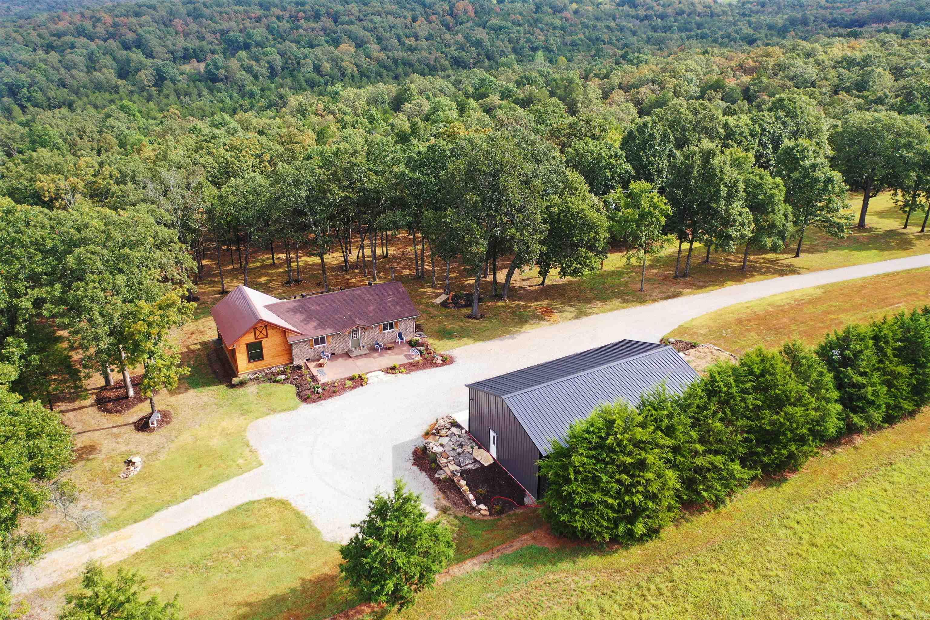 Escape to 80 acres m/l 3 miles from the Lake Norfork Boat ramp & minutes to town. Brahma Trail Ranch offers open pastures, wooded acreage, & complete privacy with a 3-bedroom, 2-bath home featuring a luxury master suite with French doors to a massive 16x45 porch overlooking rolling land, mature trees, & a cozy fire pit. Perfect for relaxing or entertaining. A three-bay 30x50 shop featuring three 10x10 doors, power & water, along with an additional 30x20 shop, provides ample space for hobbies, storage, or a home business. Two house pads have been cleared to allow you to build your family compound. Open pastures are ideal for horses, cattle, or farming if desired, while wooded areas provide excellent hunting & unmatched privacy. Springs and wet weather creek could create a pond. Many recent improvements including new heat pump, roof, inspected septic system, & a transferable termite contract make this ranch move-in ready and perfect for country living and recreation. Listed at $1,150,000