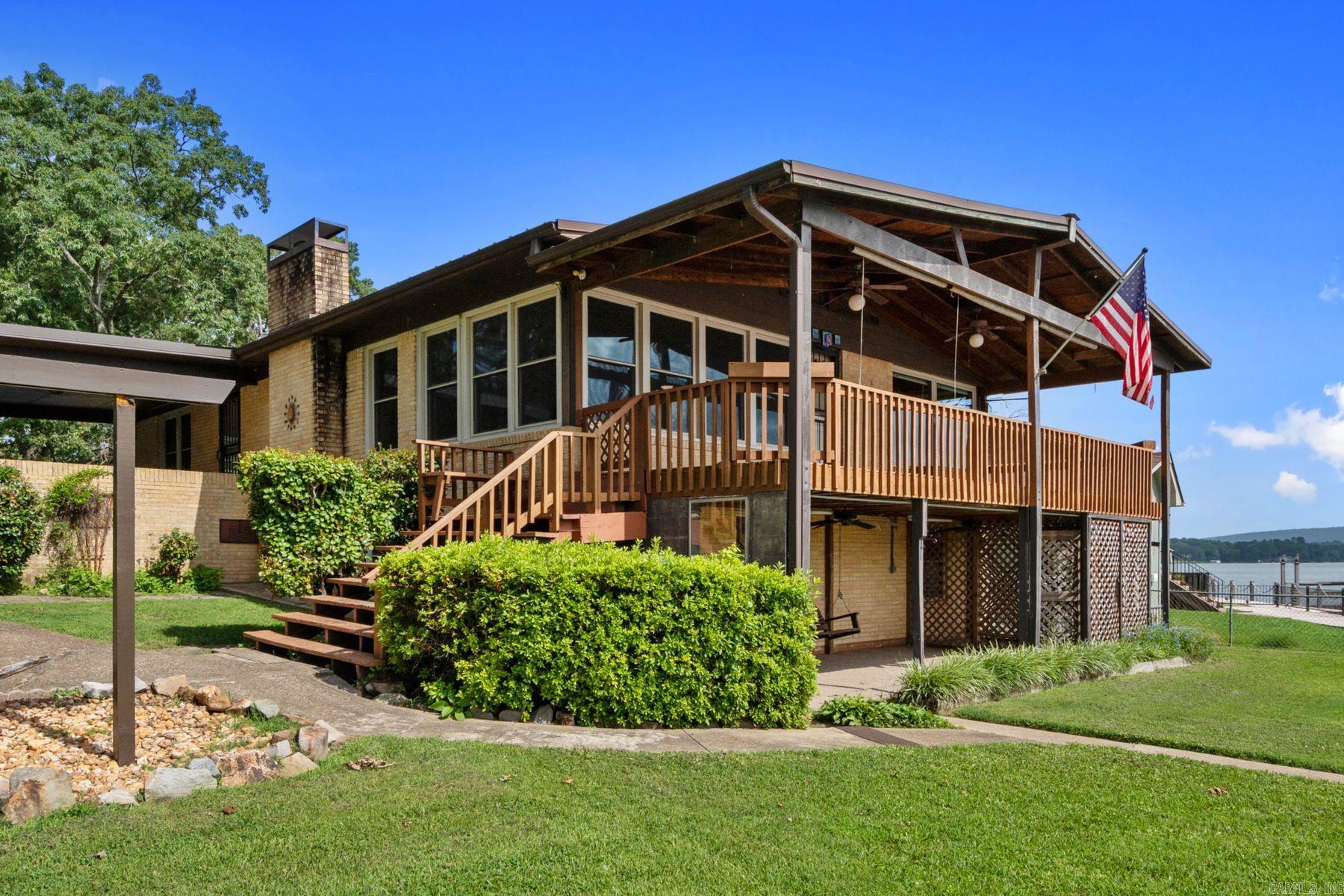 This is your opportunity to own a main-channel gem that has been cherished by its owners for over 30 years! Enjoy sweeping water + mountain views from a secluded cul-de-sac off Majestic Lodge Road, where trees canopy the street and deer roam. Be part of the action with ample room to store boats and water toys in the 2-stall covered dock, detached garage, and multiple carports. For days at home, enjoy watching water activities from your covered porch or wall-to-wall windows lining the living room and kitchen. This property has been very well-cared for. The big-ticket items have been taken care of for you, including replacement windows, a metal roof, new HVAC system, gutters, and electrical updates. There is a level, grassy lawn with a fairytale gazebo and space to add a pool if desired. Investors, this property is located outside the city limits and is not a restricted subdivision. With 5 bedrooms + a fun entertainment space with a “speakeasy” vibe, there are so many possibilities to enjoy!