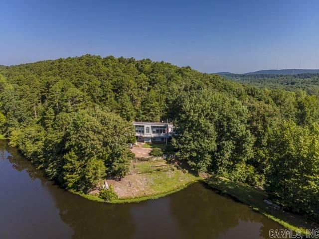 This idyllic setting boasts a home sitting on a generous 8.3 acres of land featuring a natural-fed pond and trails for exploring while only minutes to Chenal Pkwy. Property offers a serene and picturesque environment, perfect for nature lovers and those seeking peace and tranquility. The den of the house boasts large windows, strategically positioned to showcase breathtaking views of the nearby mountainsides and the picturesque pond. The primary suite is situated on the main level of the house, providing easy access and convenience. This suite has the added luxury of a separate deck that overlooks the sprawling property, allowing you to enjoy private moments with nature. The lower level of the house hosts another suite, making it a versatile space that could be used for guests or other family members. There are two more bedrooms on this level, as well as a shared bathroom to cater to the needs of the occupants. Overall, this property seems like an ideal country retreat, offering a harmonious blend of natural beauty, comfortable living spaces, and the convenience of essential amenities. If you are looking to enjoy the serenity of country living, this home is for you! *SEE REMARKS*