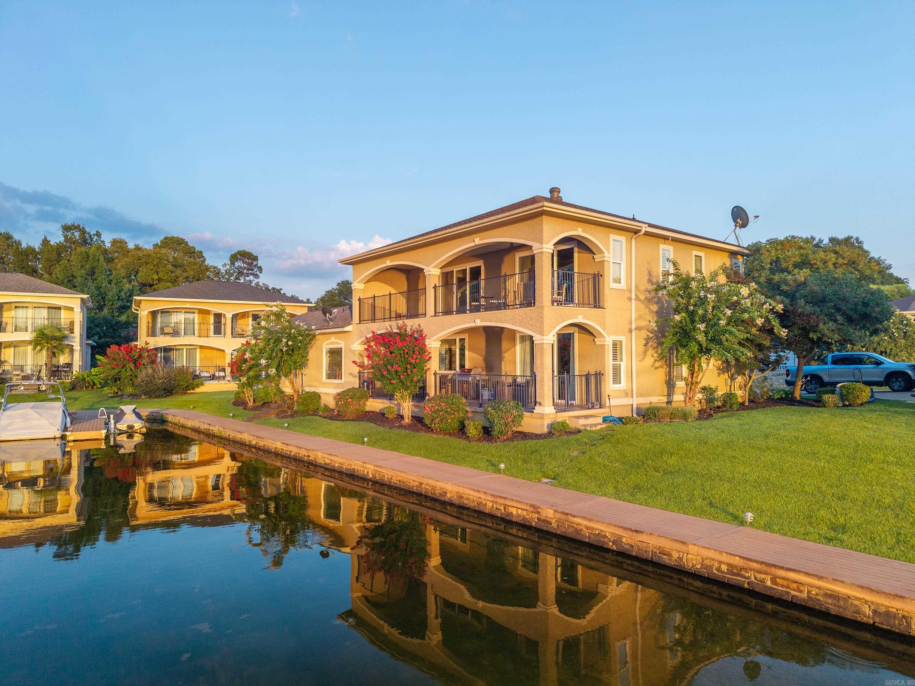 Welcome to your lakeside sanctuary where panoramic water views greet you each morning through expansive windows. This stunning 5-BR's, 3.5 Bathroom home spans 2,680 square feet of thoughtfully designed living space. The primary bedroom offers a peaceful retreat, while 4 additional bedrooms provide flexibility for family, guests. Plus, separate office. Step outside onto the large, covered patios where you can sip your morning coffee while watching the lake come alive, or host evening gatherings as the sun sets over the water. Located near the natural beauty of Garvan Gardens, this property combines tranquil lakeside living with convenient access to shopping and amenities. Whether you're seeking a permanent residence or a vacation getaway, this home delivers the perfect blend of relaxation and recreation in Hot Springs 'coveted lake community.
