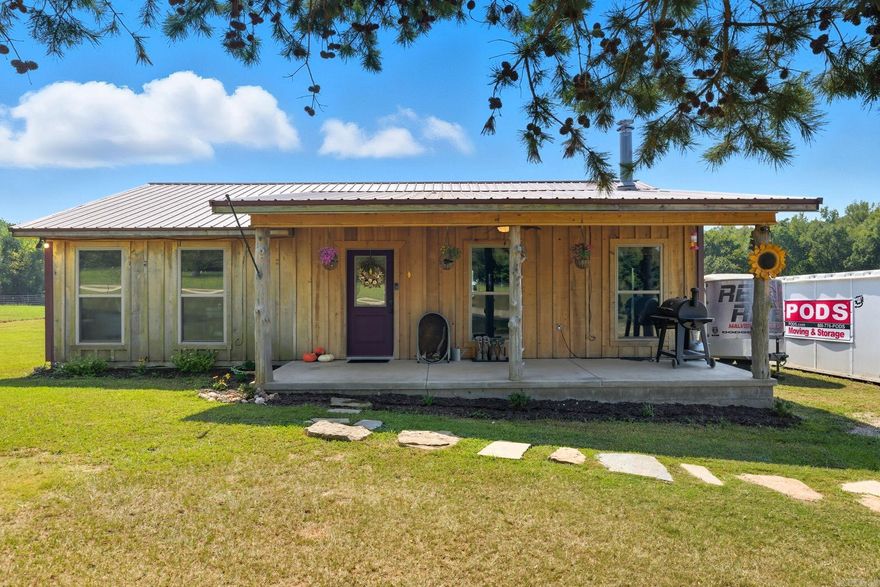 Escape to the country with this charming 2-bedroom, 2-bath cabin nestled on nearly 13 acres of serene, fully fenced land. Perfect for those seeking privacy and wide-open space, this property offers both comfort and function. The home features an inviting open-concept kitchen and living room, complete with granite countertops and a cozy pot-belly stove that creates the perfect country feel. A covered front porch provides the ideal spot to relax and enjoy peaceful views, while the land offers room to garden and space to make it your own. Equestrians and hobby farmers will appreciate the potential 10-stall horse barn, already equipped with plumbing and electricity, making it ideal for horses, livestock, or a dream workshop. Adding to the natural beauty, a seasonal creek flows through the property during rainy months, enhancing that farm charm. With plenty of room to roam, this property is a rare opportunity for those who love the outdoors and value peace and seclusion. Whether you’re looking for a private retreat, a working farm, or just a place to spread out and breathe, this unique property is ready to welcome you home.