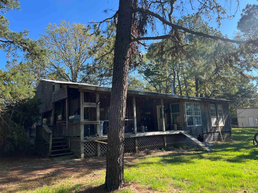 Are you looking for peace, quiet, and tranquility? This 2 bedroom 1 bath cabin and 240+- acres would be well suited for either your weekend getaway or permanent residence. The cabin even has fiber internet!   There's truly outstanding hunting on this property which is located in the Ouachita Mountains, and also fishing opportunities on your private lake complete with its own dock. (See pictures.) This property is right between and located 15 miles from both Booneville and Waldron.  The house is 1,500 sq. ft. with a 600 sq. ft. covered porch. The property also includes a 3,000 sq. ft. partially insulated metal building with a concrete floor.   There's more than enough storage for all of your toys for trail riding, hunting, and equipment for maintaining the property. In addition to a large metal storage building, there's a small metal storage building, poll barn, lean-to, and even an enclosed area with a large dock stretching out over the pond. The pond is visible and just a short walk from the log cabin.   Year round recreation is offered on this property with opportunities for fishing, hunting, trail riding, hiking, and hanging out on the front porch.