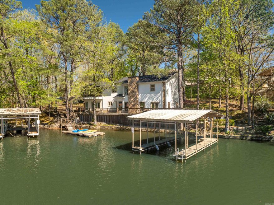 Tucked away in a peaceful cove on Lake Hamilton, this exceptional lakefront home offers the perfect blend of comfort, privacy, andincome-generating potential. Situated on just under an acre, the property has operated as a highly successful short-term rental andsleeps up to 18 guests comfortably. The home is being sold fully furnished, featuring stylish and durable furnishings, including manypieces from Pottery Barn. The main level features an open-concept kitchen, dining, living, and TV area—ideal for gathering andentertaining—with a private bedroom and a separate bunk room thoughtfully designed for kids. Upstairs, four additional bedroomsprovide ample space for guests, including a spacious primary suite complete with a spa-like bathroom and a sunroom retreat featuring asoaking tub. Outside, the property truly shines with a wraparound deck offering tranquil views of the cove, along with a hot tub, outdoorshower, fire pit, and both a covered dock with electrical and a separate swimming dock. There's also room for expansion, includingspace for an RV with electrical hookups and enough land to accommodate an additional home. Located just outside Hot Springs citylimits, the property is