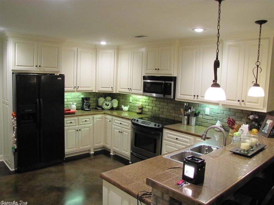 Beautiful custom built home, concrete floors, lots of trim, master suite with his/her walk in closets, jetted tub, sep shower,  granite tile countertops, w abundant cabinet space. Open living areas, split bedroom floorplan. Living Room has 10 foot ceilings, lots of Crown molding and a beautiful gas log fireplace w TV connections available above mantle. Kitchen is large with LOTS of cabinets, and dbl pantry & Breakfast bar. Nice utility room with cabinets.  Newly landscaped, privacy fenced w covered patio.