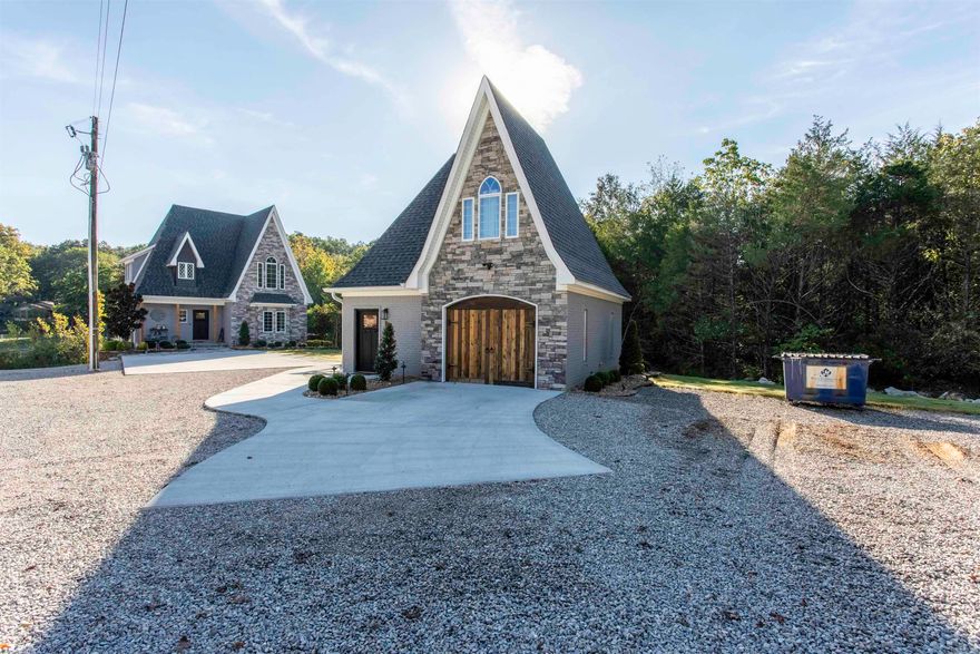 Lake House nestled at the tranquil waters edge of Lake Thunderbird in the picturesque Cherokee Village, Arkansas in Sharp County AR. This enchanting Storybook Cottage blends Whimsical charm with modern elegance. Construction completed early 2024, this newly constructed gem offers a unique and serene retreat for all who seek a peaceful escape. The main cottage consists of 2098 sq ft, 3 bed 3 Bath and the whimsical architectural details, soft gray exterior of brick and stone with a touch of cypress natural wood accents are very inviting. The lush landscaping surrounding the property enhances its fairytale allure. Open Concept with a high vaulted ceiling also accented with wood cypress beams, bathe in natural light, showcasing the high ceilings and custom finishes. The living area features a gas log fireplace and has 2 exterior doors to access the large back deck, neatly lined with steel black posts and cabling for the least amount of obstruction to the lakefront. The adjoining kitchen boast modern appliances and elegant cabinetry w Granite countertops. The detached carriage house also in similar design 1 bed 1.5 bath. Carriage house ideal for family overflow or 2nd generation family.