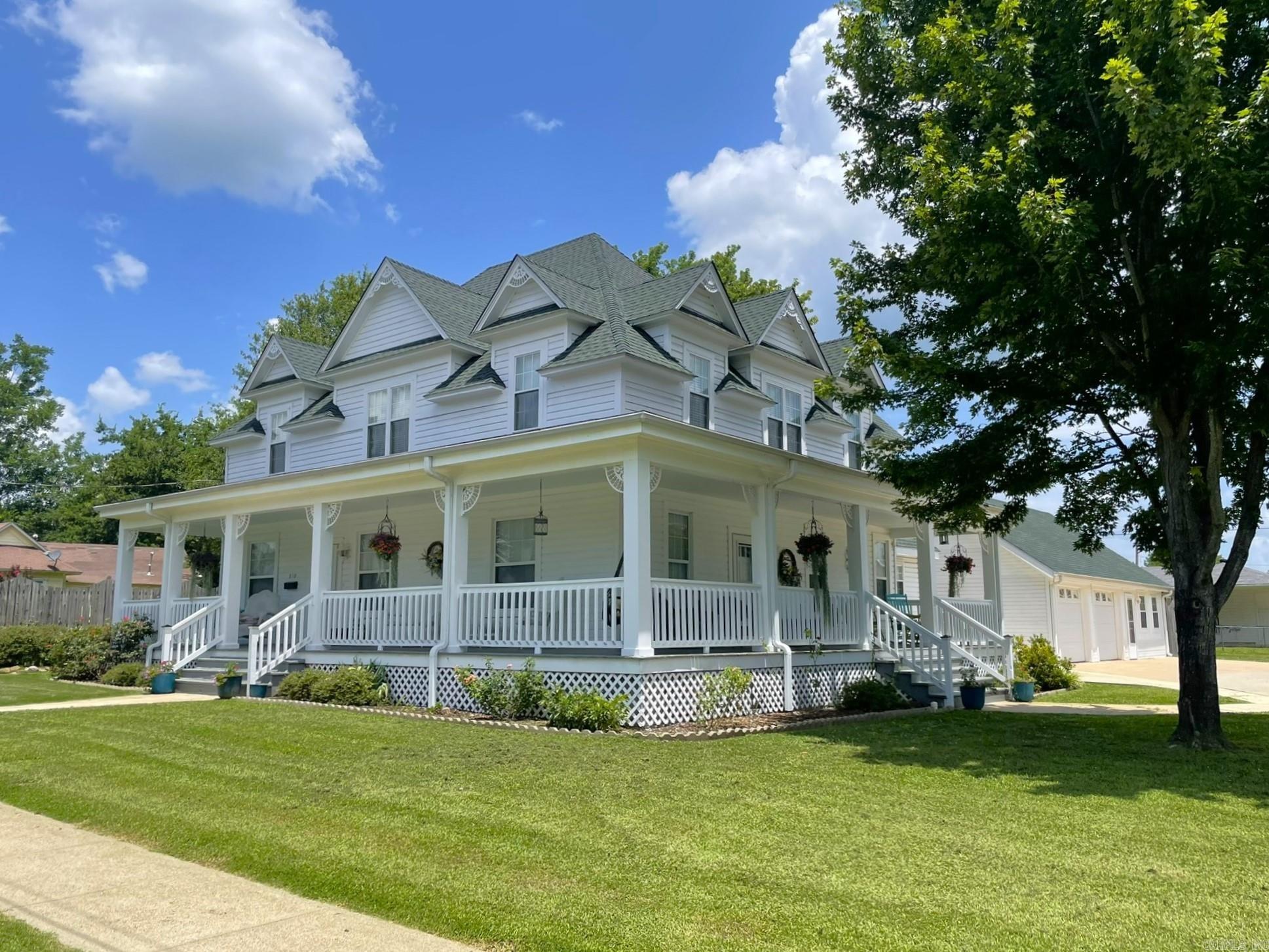 Look at this Prairie Victorian! Brand new roof, gutters, refreshed porches, screens, and more! Step into timeless elegance with this stately 5-bedroom, 2.5-bath historic home—one of Mena’s most distinguished properties. Situated on a generous half-acre corner lot, this beautifully maintained residence features 10-foot ceilings, rich architectural details, and classic charm throughout. A sweeping wrap-around front porch sets the tone, welcoming you into a gracious foyer flanked by two inviting parlors. Inside, you’ll find French doors, gingerbread trim, and period features that reflect the home's historic character. The spacious kitchen offers ample cabinetry, tile countertops, and a charming breakfast room with added storage and counter space. Other recent updates include new mini-split systems downstairs, fresh paint, and updated flooring in the bathrooms. Step outside to a beautifully landscaped backyard oasis—perfect for entertaining, relaxing, or even adding a pool. A detached two-car garage includes a versatile workshop or craft room, ideal for hobbies or extra storage. This is truly a rare opportunity to own a piece of Mena’s history with modern comforts in place.