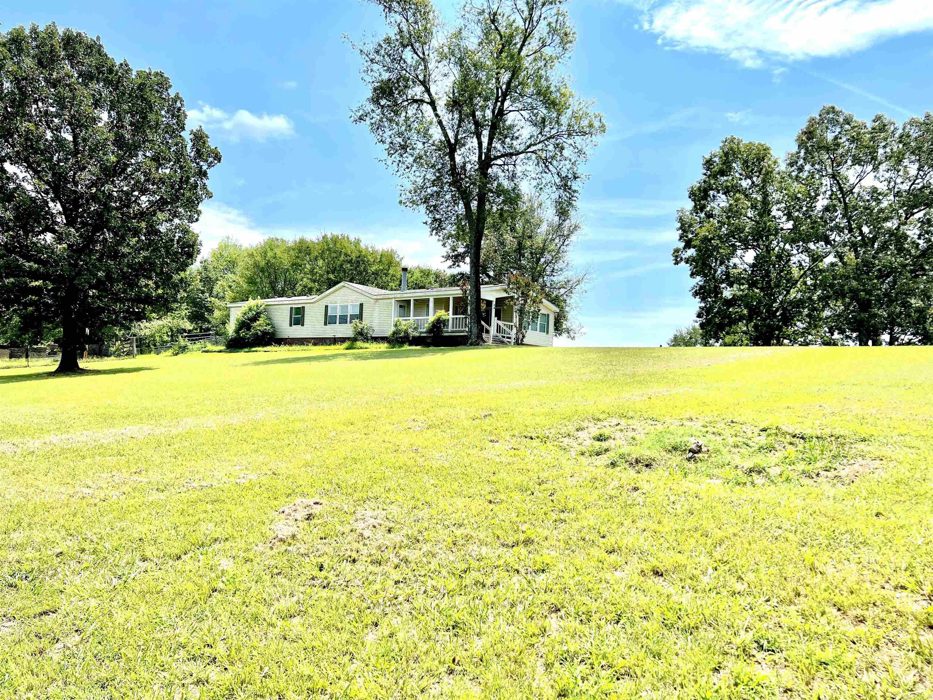 Beautiful three bed, three bath Mobile Home on six acres!! Enjoy your coffee on the back deck overlooking the property or soak and relax in the large garden tub. Kitchen has plenty of space to store appliances with two breakfast bars and a functional island. Bonus room off of Primary Bedroom great for office, craft room, etc! Primary closet is huge! Beautiful wood burning Fireplace and built in shelving in living room! Electrical post and panel newly installed in 2022 with Warranty. Storm Shelter installed in 2014. Washer and Dryer recently purchased in the fall of 2021. Additional Replacement flooring in box remains with the house.