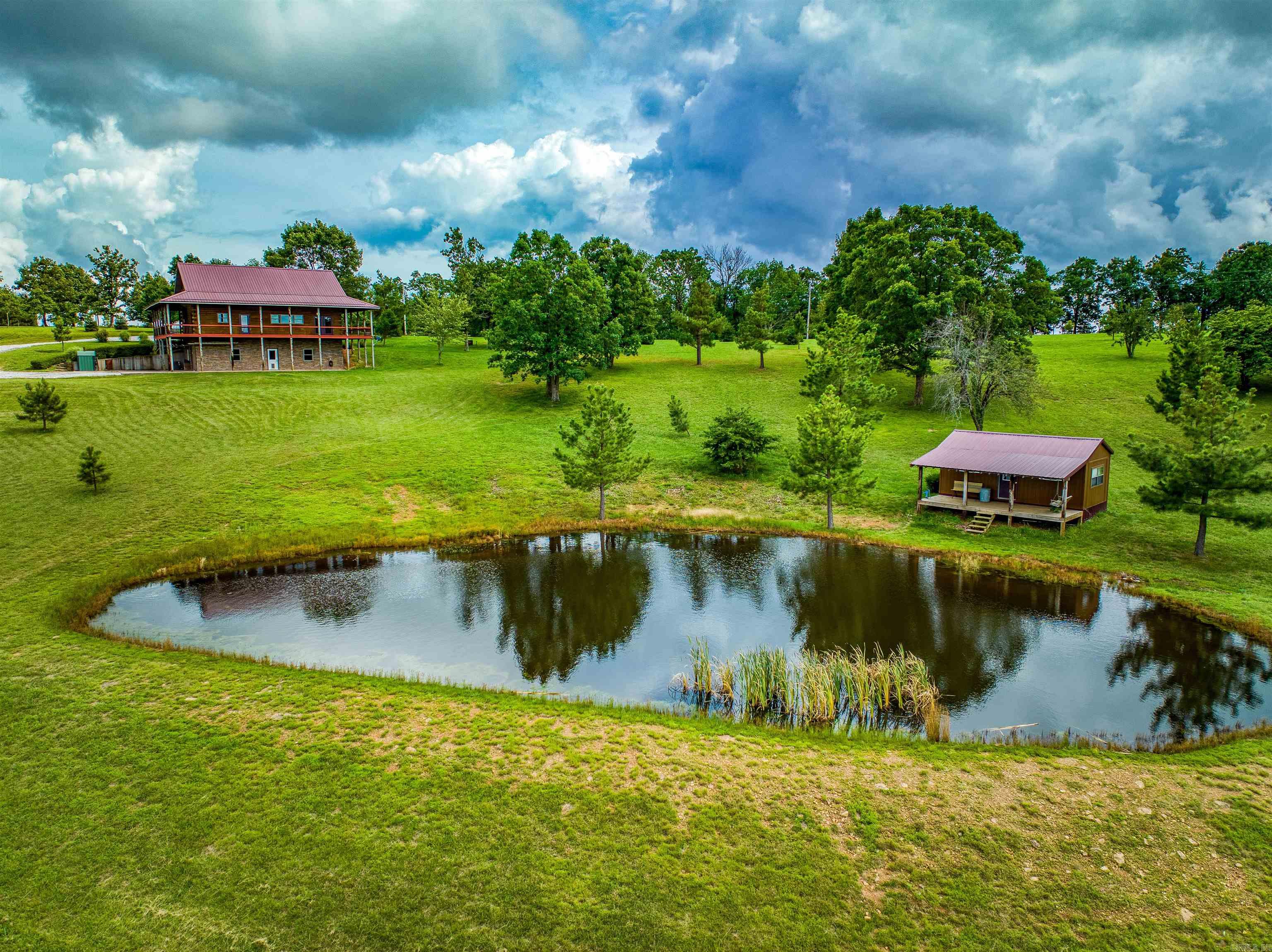 Fabulous View, must see to truly appreciate! Beautiful Northern White Pine tongue & groove D Log home covered wrap around deck situated on 9.95 park like acres w/scattered trees, large pond. Main level features open floor plan - living room, kitchen & dining perfect for entertaining w/cathedral ceilings, large windows for natural lighting, primary bedroom & bath, 1/2 bath for guest, and utility room. Upstairs features a loft, bedroom & full bathroom. Basement features heated & cooled workshop area, 1/2 bath with garage space offering plenty of room for hobbies. Looking for a little extra space take a look at the guest cabin with electric & covered front porch looking over the pond. Absolutely stunning. Home was built in 2010. Upstairs loft could be converted into 3rd bedroom. 30 Minutes to Ponca AR on the Buffalo River and just 30 minutes to Wal-Mart. Electric central heat & air and a outdoor wood burning furnace to heat the house & hot water. Manual Generator Switch in basement. See Floor Plan in Documents.