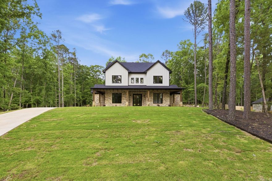Welcome to 7048 Hannah Ln, a stunning new construction home in Benton built by Homes by Jerrod, where thoughtful design meets elevated luxury. From the moment you enter through the iron and glass pivot door, you’re greeted with high-end finishes and exceptional craftsmanship throughout. The living area features a dramatic vaulted ceiling with coffered detail and a striking floor-to-ceiling white stone fireplace, complemented by custom built-ins and open shelving. Designer lighting and extensive trim work add to the home’s refined, custom feel. This versatile floor plan includes a dedicated office, workout room, and bonus room, offering flexibility for a variety of lifestyles. Enjoy outdoor living on the spacious front and back porch, perfect for relaxing or entertaining. Every detail of this home reflects a commitment to quality and design, setting it apart from typical new construction.
