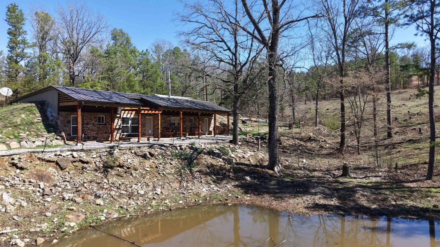 This unique 2-bedroom, 1.5-bath partially underground home on 10.69± acres offers privacy, energy efficiency, and modern updates in a rural setting. Located just 10 miles from the White River and a short drive to town amenities, this property combines seclusion with convenience. Built for durability with 6-inch poured concrete and 3-inch center block support walls, the design maintains comfortable temperatures year-round, keeping utilities low. A new fireplace in the bedroom and an additional fireplace in the main living area help warm the home during cooler months. This insulated design means very little heating is required.  The home features include oak kitchen cabinets, cedar finishes, concrete floors, and a laundry room. Recent updates include a new roof, windows, gutters, hot water heater, and appliances.  The property offers room to roam and enjoy the outdoors. That includes a wet-weather pond and a barn with electricity—perfect for livestock, storage, or a workshop.  Currently used as an Airbnb since 2024, this versatile property works great as a short-term rental or private country home in the Ozark Mountains. Listed at $169,900, with additional land available.