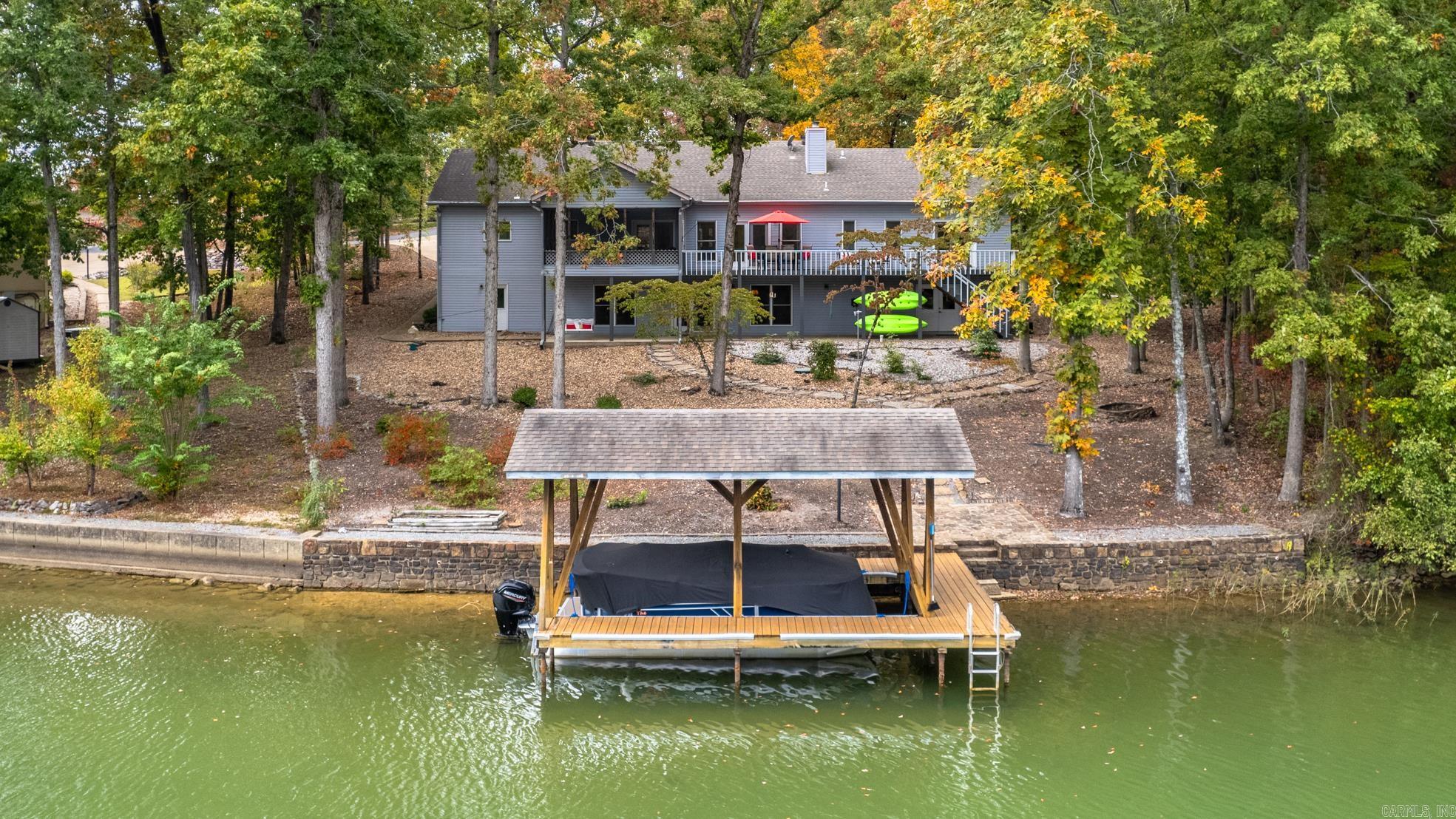 This waterfront oasis is nestled on Hot Springs Villages's largest recreational lake, Balboa. Fabulous lakefront property offering a perfect blend of casual luxury and natural serenity. With 3 bedrooms, 3 full baths, a versatile downstairs entertainment area and a private boat dock, this idyllic haven is a dream come true for those seeking the ultimate waterside lifestyle. Large windows frame the captivating lake views. It's an entertainer's delight with great flow from kitchen to living room to outside living spaces. Take your choice of dining spaces: formal dining, screened or the open porches. Enjoy days on the water, fishing, and swimming right from your own backyard. The property includes the ADJACENT LOT and many extras convey. Enjoy your pick of hundreds of amenities, social organizations and opportunities to explore nature in the United States' largest gated community. *AGENTS SEE REMARKS