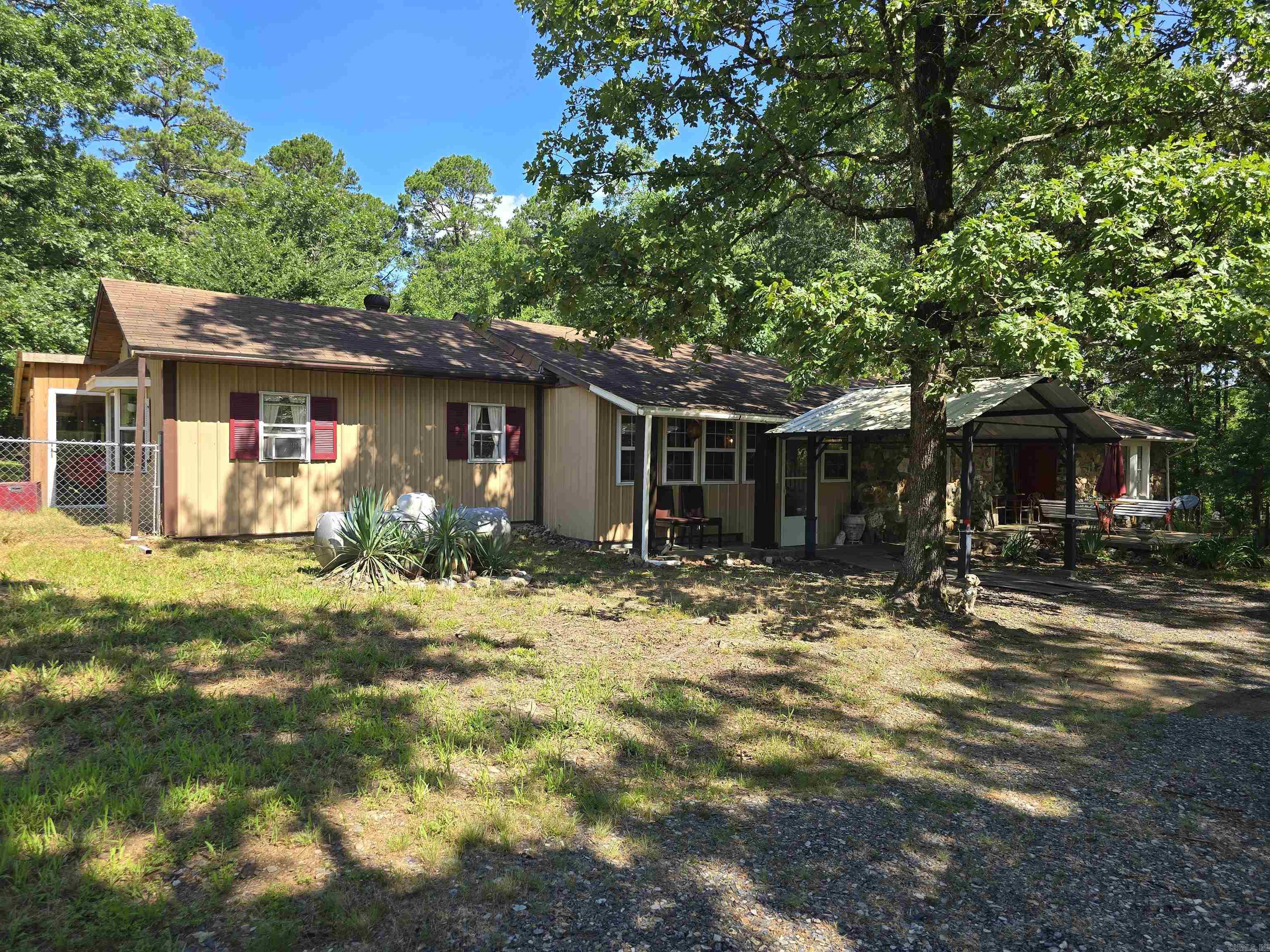 Nestled in the picturesque Board Camp Area, this charming 2-bedroom, 2-bathroom home offers a unique blend of comfort and eclectic style. Situated on 2 acres, the property provides ample space and privacy, including a partially fenced backyard perfect for pets or outdoor activities. Step inside and be greeted by a striking entry featuring a beautiful rock wall, setting the tone for the home's distinctive character. The interior boasts an efficient layout with a dedicated office area, ideal for remote work or creative pursuits. A large laundry room adds convenience to daily living. Outdoors, you'll find a welcoming patio in the front yard, perfect for enjoying your morning coffee or evening sunsets. A useful storage building in the backyard provides extra space for tools and equipment. One of the property's prime features is its proximity to the Ouachita River, just 1.7 miles away, offering easy access to fishing, kayaking, and other recreational activities. This home is a true gem for those seeking a tranquil retreat with unique style and convenient access to nature.
