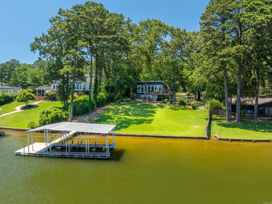 Amazing 1 acre property just off the main channel on Lake Hamilton. The property has 3 dwellings that sleep a total of 16+ people. The property has been a very successful short term rental & is being sold fully furnished w/ most furniture from The Pottery Barn. The main house (1,628 sqft) is exquisite w/ a large open living, dining & kitchen and has a wall of windows overlooking the lake. The kitchen is very open, has stainless steel appliances & a quartz island. The primary bedroom is on the main floor along w/ a bath. The lower floor has a bunk room, bedroom & full bath with a W&D. The cottage(408 sqft) has a kitchenette w/ electric cooktop, refrig, sink & dishwasher. The third house(1,376 sqft) has 3 bedrooms, 2 baths & wonderful kitchen w/ butcher block cntps & laundry w/ a W&D. The property is one of the best of the lakes, is fully fenced & has a large yard that leads down to the lake with enough room to add a pool. The large deck on the main house has plenty of seating, breathtaking views of the lake. A covered boat dock, sprinkler sys & hot tub are also on property. The property is  outside the Hot Springs city limits & does not require a license for short term rental use.