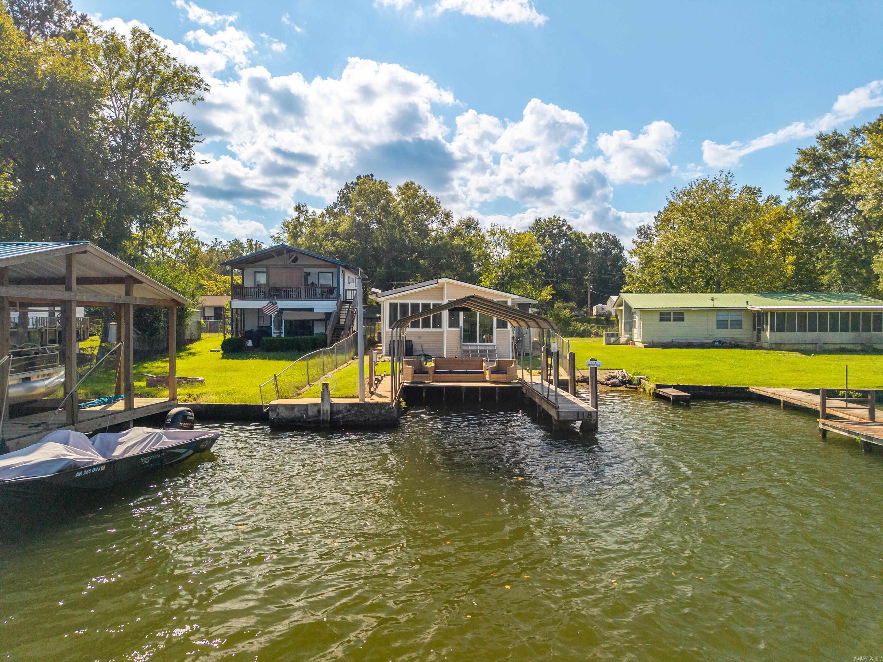 ~Deep Water. Covered Dock. Bonus Lake Lot. Turnkey Investment Under $400k!~ This turn-key Lake Hamilton cottage is located on the main channel and includes an additional lake-front lot, offering abundant investment potential. The property includes a covered boat dock w/jet ski lift, a fully-fenced & gated yard, and a separate storage shed with electricity - which could easily be converted into a guest suite or she-shed. Inside, the 3-Bedroom, 2-bath home features an open/airy floor plan with a screened front porch/mud room, and a sunroom with an eat-in bar to enjoy dinner and lake views year-round. You'll appreciate the newly-installed UV-blocking blinds, keeping the sunroom cool & comfortable, even on the brightest Summer days. Sellers spared no expense on all new furnishings, decor, and a fully-equipped kitchen. Home was renovated top-to-bottom late 2023, including a new roof. Don't miss the opportunity to have a darling Lake Hamilton home at an affordable price. Agents see remarks.