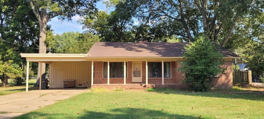 Phenomenal opportunity for buyers willing to put some sweat equity into repairs for a great return on investment! This 2 bedroom, 2 bath brick home needs a new roof and some updates, but the curb appeal, retro vibes, and amazing outdoor space should put this home on your list of must-see properties. In addition to the large living room, there's also a fantastic space with wood-burning fireplace and wood plank paneling that provides a cozy setting for a den, office or dining area. The  house sits on 4 city lots and runs from Seaman St in the front to Johnson St in the back! There is ample storage inside - primary bedroom has 3 closets - with a nice outside storage room off the double carport. Other exterior features include an inviting front porch and a sidewalk winding around the south end of the home that leads to a spacious outdoor area that just needs a little cleaning and a bit of vision to make it your go-to spot for entertaining.  Great location next to McCrory High School is a plus.