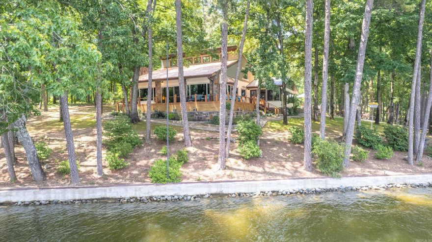 Lakeside Oasis! Just steps from 481' of prime Lake Hamilton shoreline. This beautiful home is nestled on almost 2 ac of tree studded seclusion with 270° views of the water. A warm and inviting modern, farmhouse chic décor welcomes you from the moment you step through the door. Perfect for entertaining, the large open living/dining area opens to the wrap around deck for those stunning sunrise views. Granite counters, custom cabinetry and hardwood floors are just a few of the reasons you'll feel like you're living in a resort. The downstairs master en’suite offers a lodge feel with high wood ceilings and best of all you'll wake every morning with the lake as your focal point. The upstairs master en’suite offers a birds eye view of the water nestled in the tree tops. The property features extra landscaping, lush green lawn, a detached workshop/garage and lakeside patio at the covered boat dock. Your summer never looked so good! Boat and furnishing can be purchased separately. Schedule your private showing today!