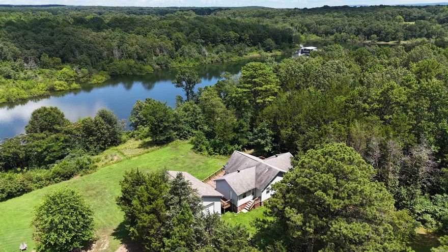 Nestled along the serene shores of the expansive 47,000 acre Greers Ferry Lake, this exquisite 3-bedroom, 2-bathroom home offers unparalleled access to the pristine waters of the Ozark Mountains. Situated on Hurricane Bay Channel, own for its fishing & swimming opportunities.  Step from your backyard off from the large wooden deck, where you can Enjoy breathtaking sunrises and sunsets right into the lake! The home's interior boasts soaring 18-foot vaulted ceilings and an open floor plan, complemented by floor-to-ceiling windows that flood the space with natural light and offer panoramic lake views. A spacious 2-car garage provides ample room for your surf boat and all your lake toys, ensuring you're always ready for a day on the water. Located just around the corner from Lacey's Marina, you'll have convenient access to boat rentals, supplies, and services. Additionally, a nearby national park offers RV parking and a boat ramp, enhancing your outdoor recreation options. Please note that current photographs may depict a brownish water hue due to the rainy season. Rest assured, as the rainy season concludes, Greers Ferry Lake transforms into a crystal-clear oasis!