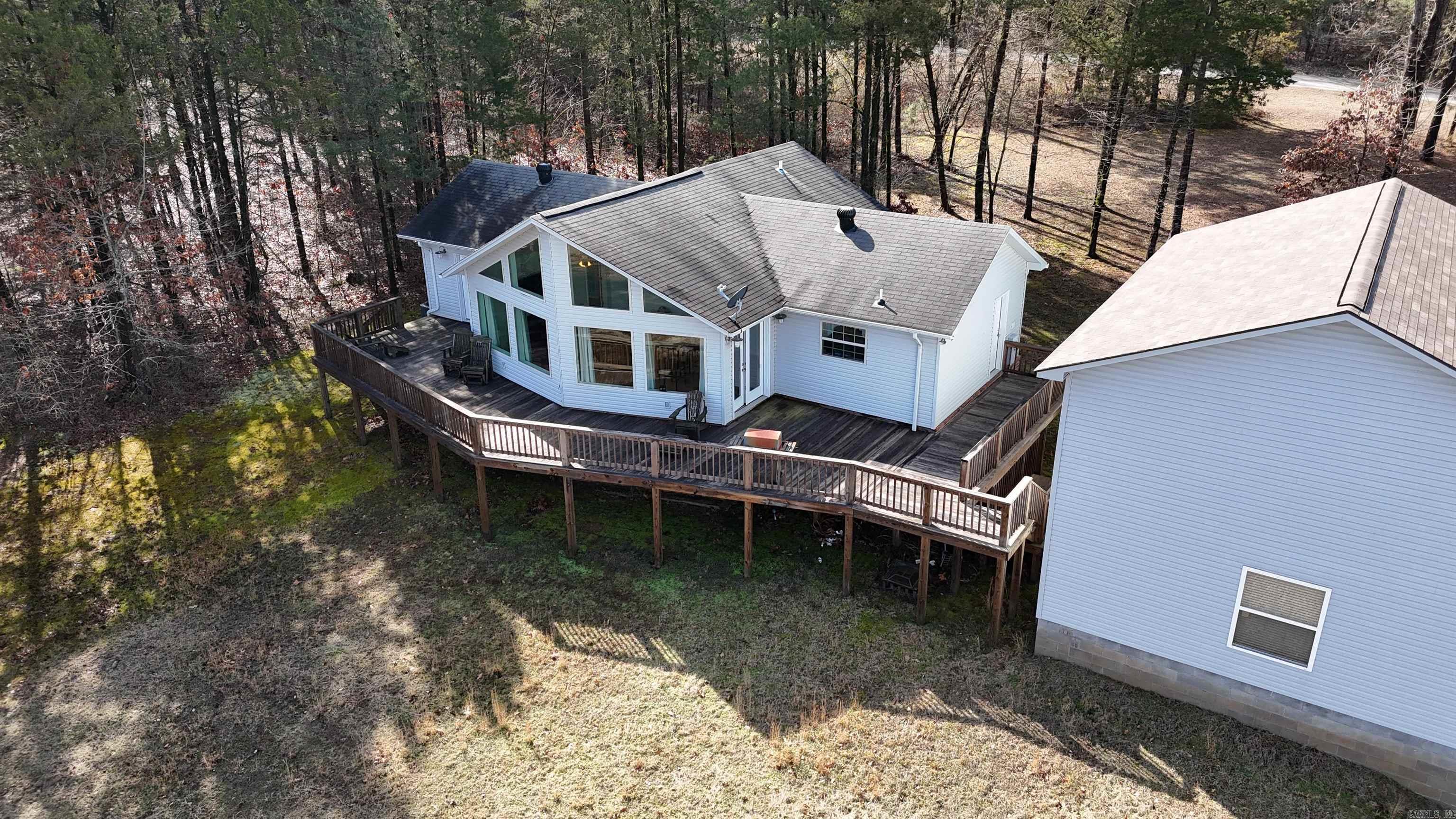 Nestled along the serene shores of the expansive 47,000 acre Greers Ferry Lake, this exquisite 3-bedroom, 2-bathroom home offers unparalleled access to the pristine waters of the Ozark Mountains. Situated on Hurricane Bay Channel, own for its fishing & swimming opportunities. Step from your backyard off from the large wooden deck, where you can Enjoy breathtaking sunrises and sunsets right into the lake! The home's interior boasts soaring 18-foot vaulted ceilings and an open floor plan, complemented by floor-to-ceiling windows that flood the space with natural light and offer panoramic lake views. A spacious 2-car garage provides ample room for your surf boat and all your lake toys, ensuring you're always ready for a day on the water. Located just around the corner from Lacey's Marina, you'll have convenient access to boat rentals, supplies, and services. Additionally, a nearby national park offers RV parking and a boat ramp, enhancing your outdoor recreation options. Please note that current photographs may depict a brownish water hue due to the rainy season. Rest assured, as the rainy season concludes, Greers Ferry Lake transforms into a crystal-clear oasis!