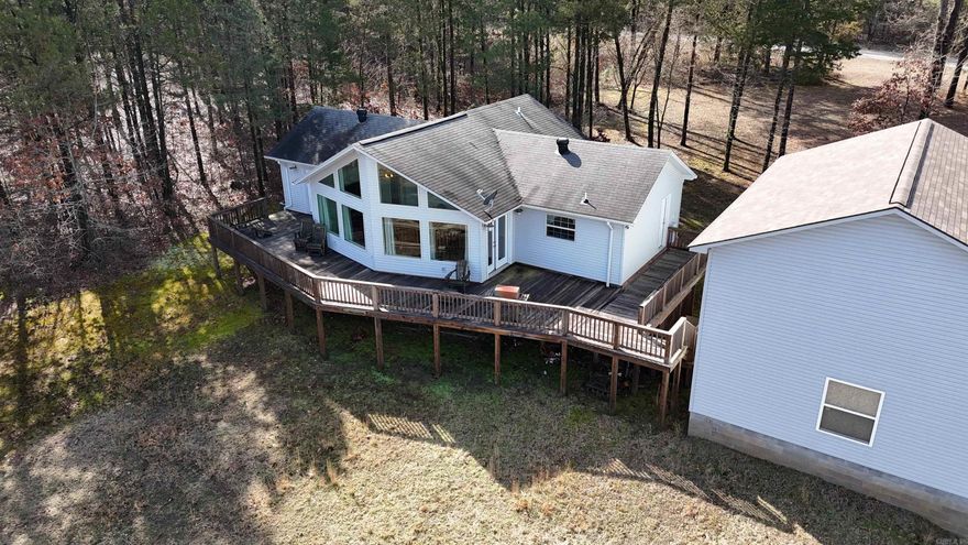 Nestled along the serene shores of the expansive 47,000 acre Greers Ferry Lake, this exquisite 3-bedroom, 2-bathroom home offers unparalleled access to the pristine waters of the Ozark Mountains. Situated on Hurricane Bay Channel, own for its fishing & swimming opportunities.  Step from your backyard off from the large wooden deck, where you can Enjoy breathtaking sunrises and sunsets right into the lake! The home's interior boasts soaring 18-foot vaulted ceilings and an open floor plan, complemented by floor-to-ceiling windows that flood the space with natural light and offer panoramic lake views. A spacious 2-car garage provides ample room for your surf boat and all your lake toys, ensuring you're always ready for a day on the water. Located just around the corner from Lacey's Marina, you'll have convenient access to boat rentals, supplies, and services. Additionally, a nearby national park offers RV parking and a boat ramp, enhancing your outdoor recreation options. Please note that current photographs may depict a brownish water hue due to the rainy season. Rest assured, as the rainy season concludes, Greers Ferry Lake transforms into a crystal-clear oasis!
