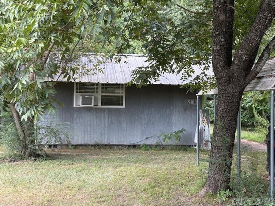 JUST REDUCED! Large single room with a divider for a sleeping area. Bathroom with a shower stall. Heating and air conditioning provided by a window mounted heat pump, new in 2024. Rear porch. Large carport able to accommodate a boat and car. Over a half acre of land, a utility building and a fenced rear yard. Property includes a hard wood table, a small microwave, a small dishwasher, a 3 burner propane stove and some dishes, a coffee maker and silverware. Two large area rugs convey. There is a small chest freezer on the rear porch and a self-propelled lawn mower.