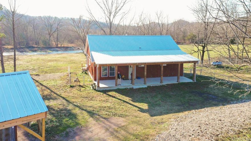 Situated on the banks of the beautiful, clear Caddo River, this unique property offers approximately 68.64 acres with land extending on both sides of the river, providing exceptional privacy and stunning natural surroundings. The home features an open floor plan designed for gathering and entertaining, highlighted by a large kitchen island with ample seating. Interior finishes include durable finished concrete flooring, a wood-burning stove, and an expansive wall of windows that frame breathtaking views of the river.  Additional living space includes a finished sunroom perfect for enjoying the scenery year-round. Outdoor features include two spacious decks and a fenced yard, creating ideal spaces for relaxing or hosting.  The property is well equipped for livestock, hobbies, or storage with a two-stall barn that includes a tack room, feed room, and workroom. The barn also features covered RV parking on a concrete slab, adding convenience for recreational or travel use.  With extensive river frontage, versatile acreage, and functional improvements, this rare property offers the perfect blend of country living, recreation, and privacy.