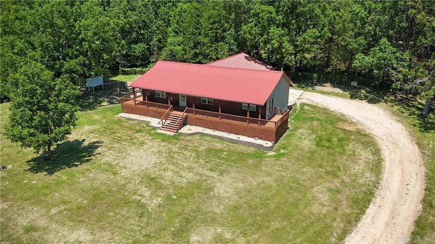 Rural, spacious, and practical. This updated 5-bedroom, 3-bathroom home offers over 2,300 sq ft of living space on 1 acre, minutes from Harrison. The open-concept design connects the living room with its cathedral ceilings and gas fireplace to the farmhouse-inspired eat-in kitchen, creating an inviting atmosphere for gathering or entertaining. The primary suite features a private bathroom, walk-in closet, cathedral ceilings, and a private exit onto the wraparound deck that adorns the front of the home. Notable attributes include a pull-through attached two-car garage, attached metal workshop area, metal roof, low maintenance vinyl and log siding, and a long private driveway with a gate, all in a desirable school district. This home combines the best of country living with modern efficiency.