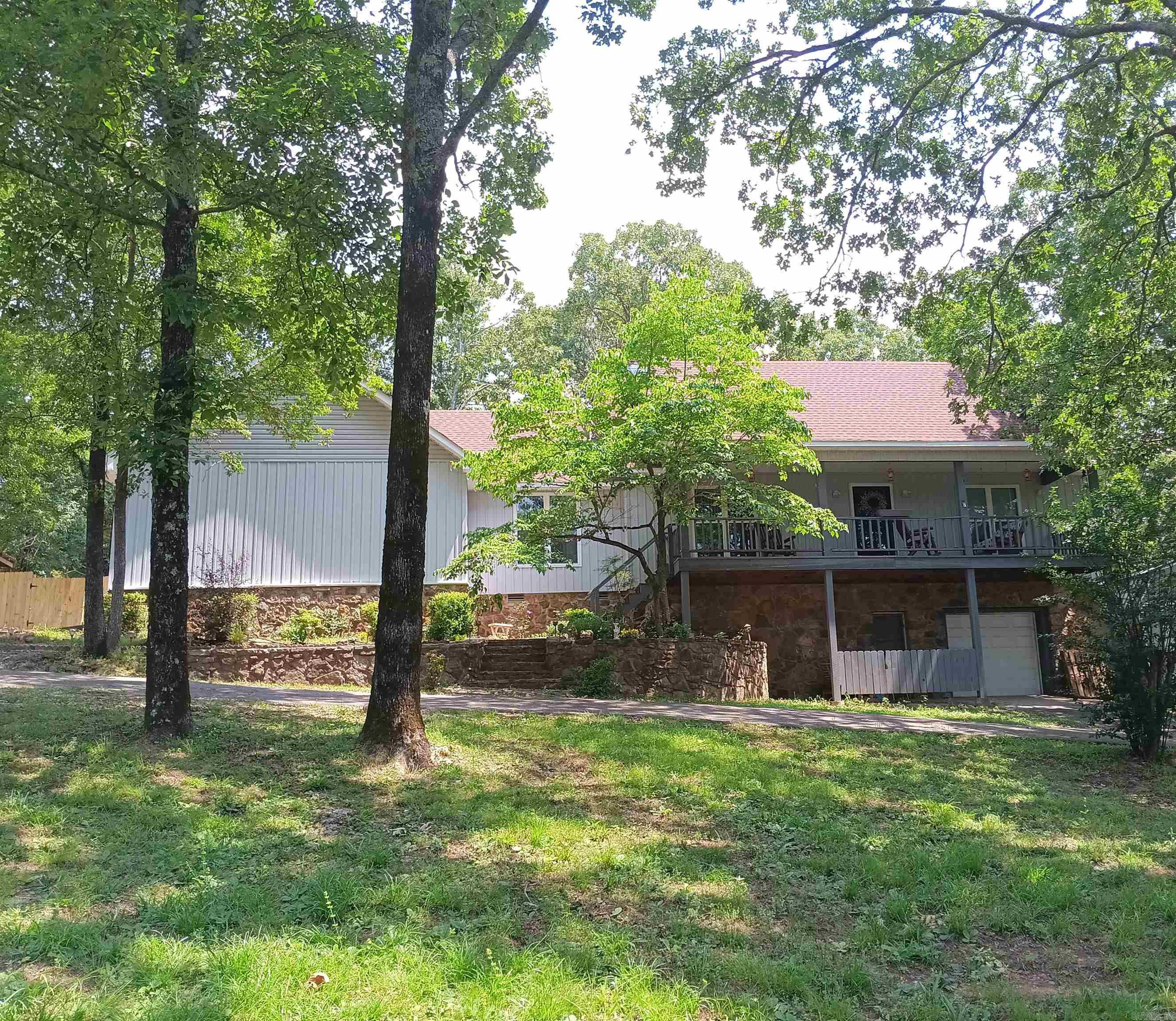 This well-built 2 story house also has a walk out basement. Many updates including vinyl windows, vinyl siding, cedar planks on deck, new wood privacy fence around the back yard & more. This 1.22-acre paradise has a top floor deck off the back & an elevated covered porch off the front to drink coffee & relax in the shaded view. Stone fireplace, 2 car garage, separate laundry with sink, separate dining room, large living room with dual ceiling fans, main bath has a jacuzzi tub, lots of counter space & storage with walk-in closets. The basement can be used as living space as it has window unit & heater but could also be a shop, storage or game room. It has a 1/2 bath in basement also. See agent remarks.
