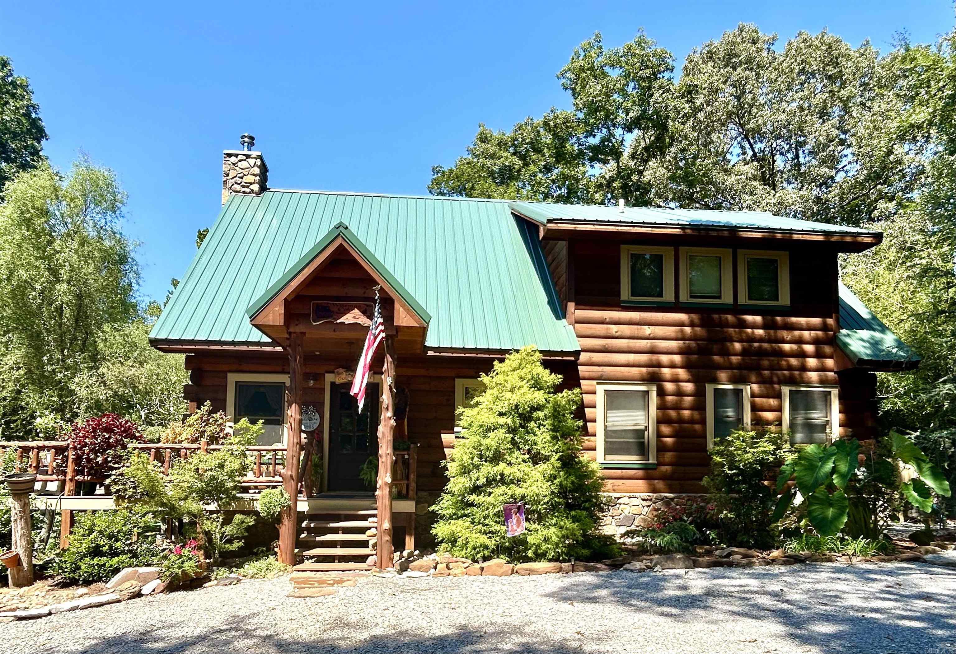 Stunning log home on the creek! This handsome, beautifully crafted, and well maintained 3 bedroom and 2 bath log house sitting above Lick Fort creek is the Ozark Mountain home that you dream of. Here is a home for all the seasons. Year round, from the sunny open deck or the generous covered back porch you can hear and watch the water flowing through the creek. The professionally landscaped gardens will delight you with a profusion of blooms in the spring, vibrant flowers and plenty of shade in the summer, and brilliant fall colors. Enjoy cold winter days indoors by cozying up next to the stately stone fireplace or surveying the estate through the many large windows. Meander on down to the waters edge anytime. The water is clear and the creek bottom is stone. Inside is just as delightful with soaring ceilings, wood floors, open layout kitchen and great room with the stunning stone fireplace, two bedrooms (one of which opens onto the back porch, a great place to enjoy your morning coffee!), a full bath, and a laundry area downstairs. Upstairs is the large primary bedroom and bath with double vanities, clawfoot tub, and separate shower. Located only 4.4 miles from downtown Mtn View!