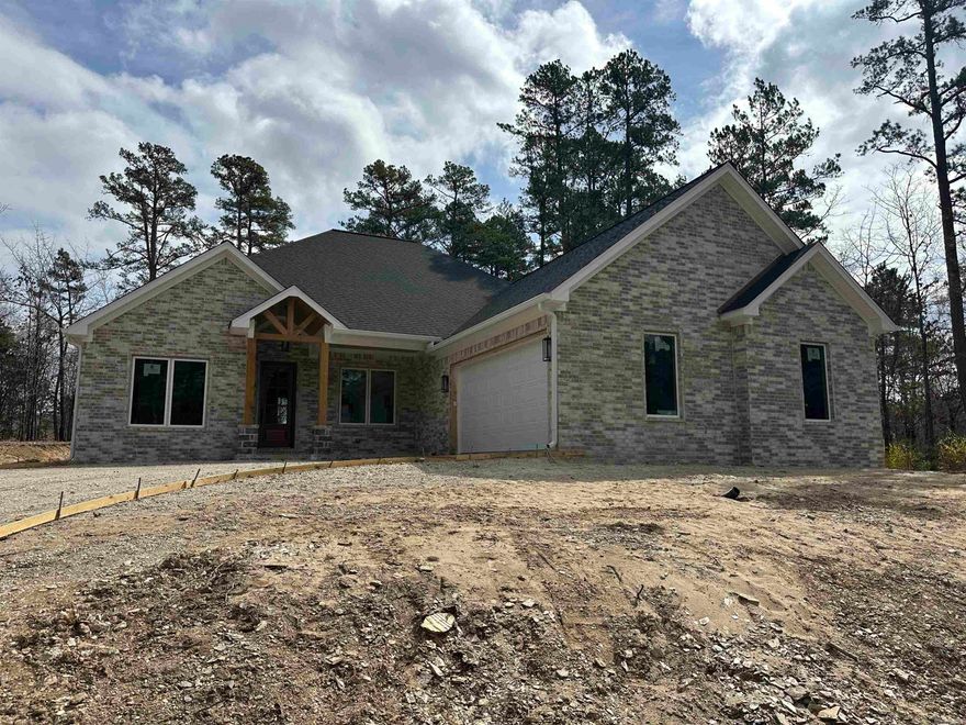 Welcome to this beautiful new construction home in Hot Springs Village, perfectly situated just minutes from the Balboa Gate, Balboa Beach, and three nearby golf courses. This thoughtfully designed 3 bedroom, 2 bath home with a dedicated office sits on a level lot and offers both style and functionality.  Inside, you’ll find an open layout with crown molding throughout, a gas fireplace with electric igniter, and a well-appointed kitchen featuring Taj Mahal quartz countertops and Frigidaire Professional stainless steel appliances. The split-bedroom floor plan provides privacy, while the spacious master suite offers double vanities, a soaking tub, custom tile shower, and a large walk-in closet that connects to the laundry room.  The oversized two-car garage opens to a mudroom entry, creating a practical drop zone before entering the main living areas. Outdoor living is inviting with tongue-and-groove pine ceilings on the porch and a durable brick and stone exterior.  Built for comfort and efficiency with a 16-SEER HVAC heat pump, 50-gallon hot water heater, and 30-year architectural shingle roof, this home combines quality construction and fantastic location.   SEE AGENT REMARKS