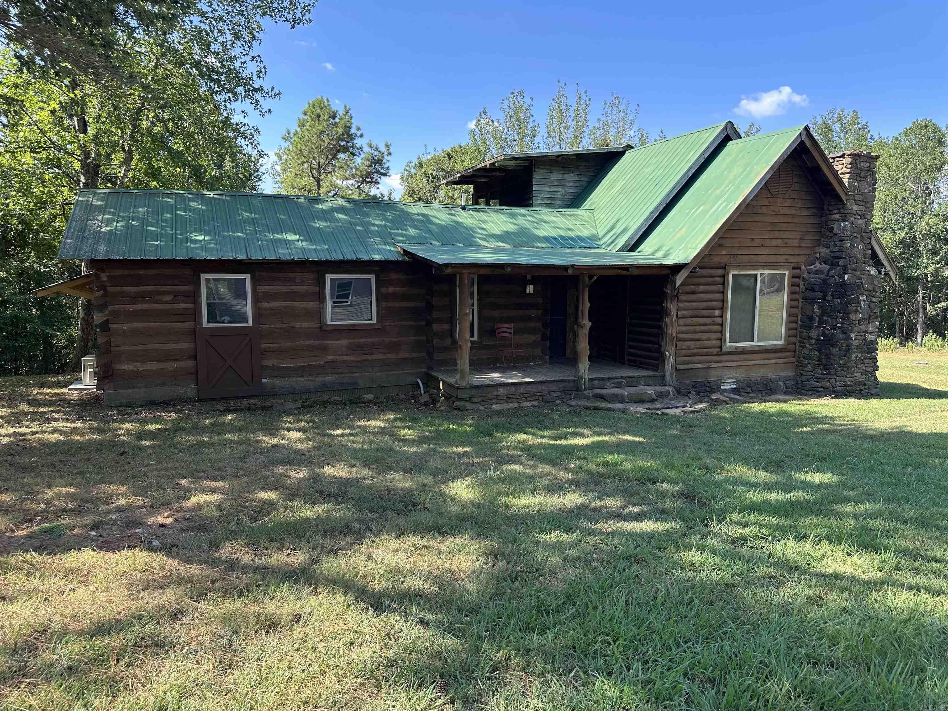 41.76 rolling acres of scenic Arkansas land featuring a rustic log cabin (approximately 1605 sq. ft. thatās divided into a studio living space (432 sq. ft. heated & cooled) on one side and a storage area (1173 sq. ft) on the other. The cabin sits tucked back from the road, offering peace, privacy, and immersion in nature. A fully fenced orchard (135ā x 85ā) hosts a variety of 3-year-old fruit treesāincluding apple, peach, pear, plum, cherry, jujube, may haw, pawpaw, and mulberryāalongside rows of thornless blackberries, elderberries, and blueberries. Nearby, a fenced garden area (75ā x 50ā) contains 12 raised beds for easy planting and maintenance, also protected by 6-foot woven wire fencing. The property includes several additional structures: a 40ā x 30ā garage ideal for storage or workshop use, a 15ā x 10ā greenhouse for extending the growing season, a 40ā x 15ā RV pole barn, a 30ā x 25ā smaller pole barn suitable for animals or tools, and a spray-foamed 25ā x 12ā well house with a 1,500-gallon holding tank. Bonus features include wild black walnut, black cherry, raspberries, blackberries, and a wealth of native medicinal plants found throughout the land.