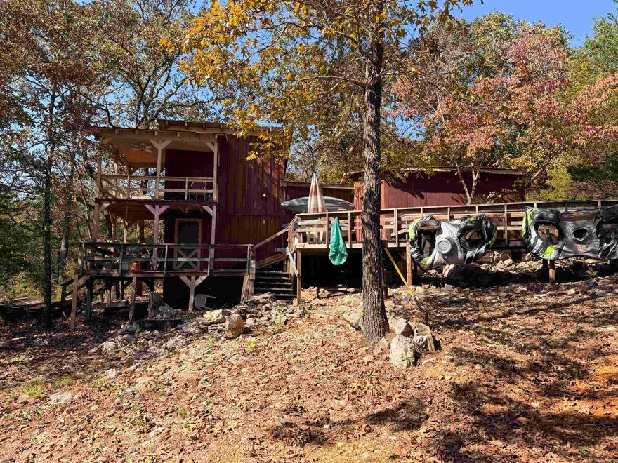 Escape to the quiet beauty of the Ozarks with this rustic cabin retreat surrounded by mature hardwoods and peaceful scenery. The 1.5 story cabin you will never want to leave features wraparound decks, and multiple outdoor sitting areas perfect for soaking in nature. Inside, you’ll find charming vintage details throughout—from exposed wood beams and barn-style built-ins in the living area to the retro green kitchen with wood-planked ceilings that add warmth and character. Offering 2 sleeping areas, a full bath, and a cozy living space, this property makes an ideal weekend getaway, hunting cabin, or investment for short-term rental potential. Enjoy privacy, wildlife, and the sounds of nature from every angle. Located just minutes from the Spring River and several parks, this property is ideal for anyone who loves fishing, kayaking, or exploring the great outdoors. Enjoy the quiet privacy of the woods while still being close to dining, shopping, and local attractions.