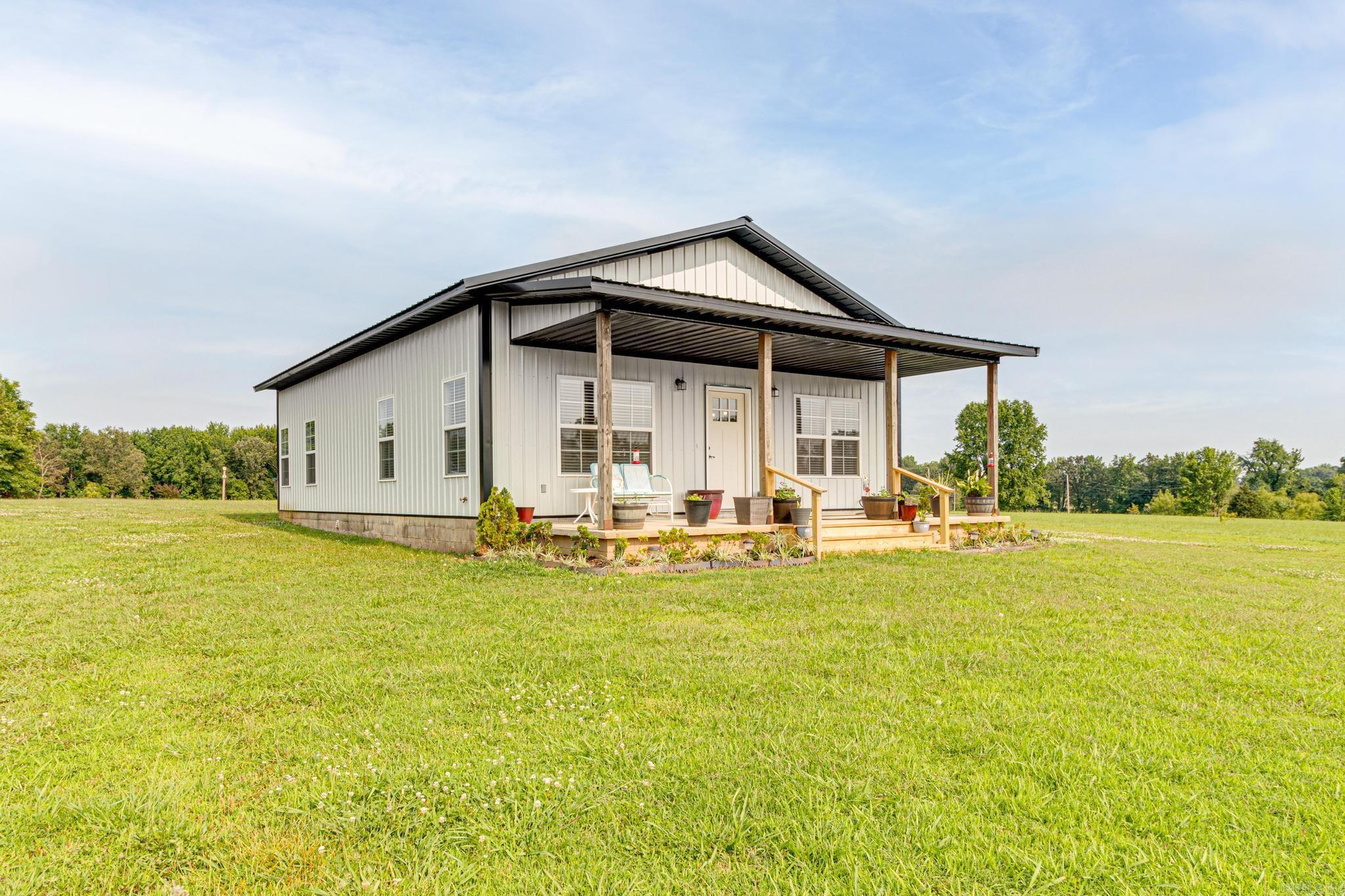 Cozy meets country and metal meets modern in this alternative style home located off Campground Road. This adorable metal home has 2 bedrooms/2 baths is 1200 square feet but feels larger inside with it's 10 foot ceilings, open concept floor plan and windows galore! Interior features lighter colors, 2" blinds and luxury vinyl flooring throughout. Professional-grade kitchen has granite countertops, white cabinets with "soft close" doors/drawers and matching stainless appliances including the refrigerator that conveys with the property as well as a wine/beverage (bar) fridge plus wall oven in addition to cookstove! Primary bedroom has en-suite bath with tiled shower, closet and long vanity. Exterior features almost 3 acres and large inviting front porch and even though it feels like country .... you have city utilities and paved roads!! Make the drive to check this one out then call to schedule your personal tour with me or your favorite real estate agent.