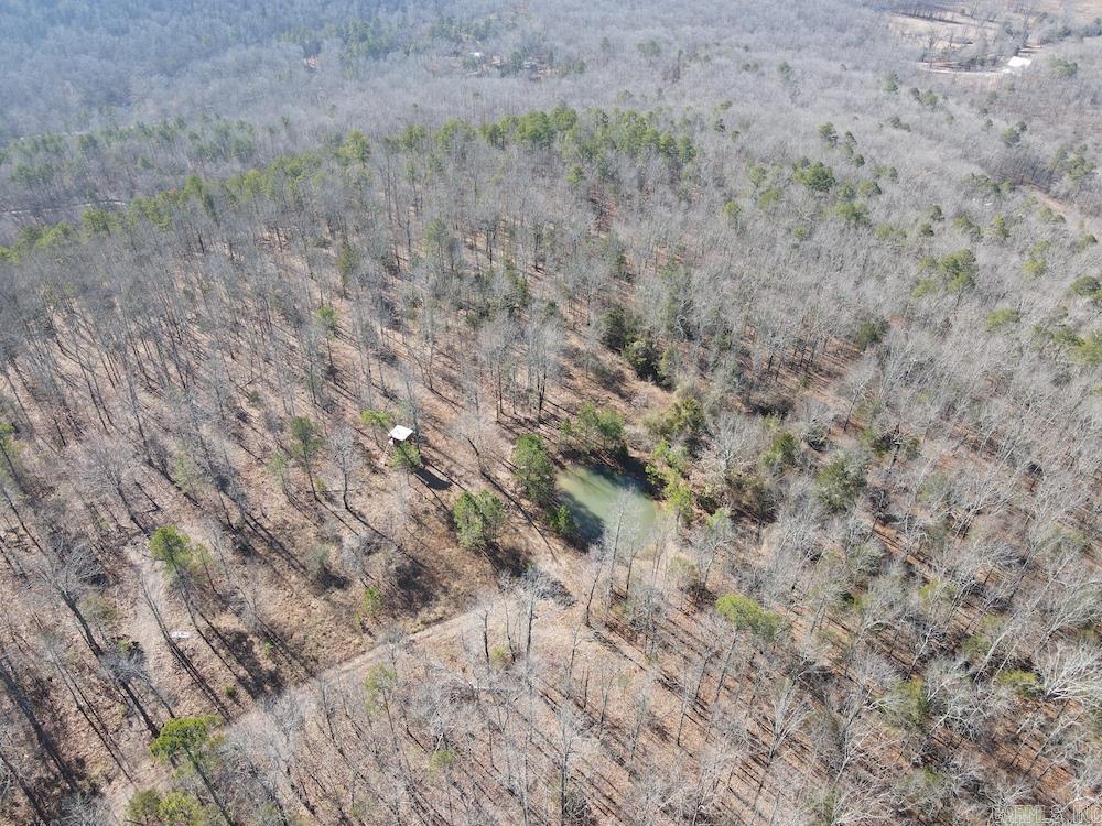 This 40-acre hardwood timber tract near Mountain View, AR, is a secluded off-grid retreat perfect for hunters, preppers, and nature lovers. Accessed via a private deeded easement, the property sits atop a mountain offering total privacy, scenic beauty, and diverse terrain with ridges, flats, and elevation changes. It features mature hardwoods, unique rock bluffs, a serene pond, and a well-maintained ATV/UTV trail system. Wildlife is abundant—big whitetail bucks, black bear, turkey, and small game frequent the area. A recently built 4x8 elevated box blind offers great views of the timber, pond, and clearings. A concrete pad is already in place for a camp or future build. With no utilities or restrictions, it’s ideal for camping, hunting, or building your own off-grid hideaway. The massive rock bluff on the west side offers both natural beauty and strategic hunting spots. Despite its seclusion, it's only 20 minutes from Mountain View and 30 minutes to the White River, Blanchard Springs Caverns, and the Ozark National Forest. Rare chance for freedom and self-sufficiency in the Ozarks.