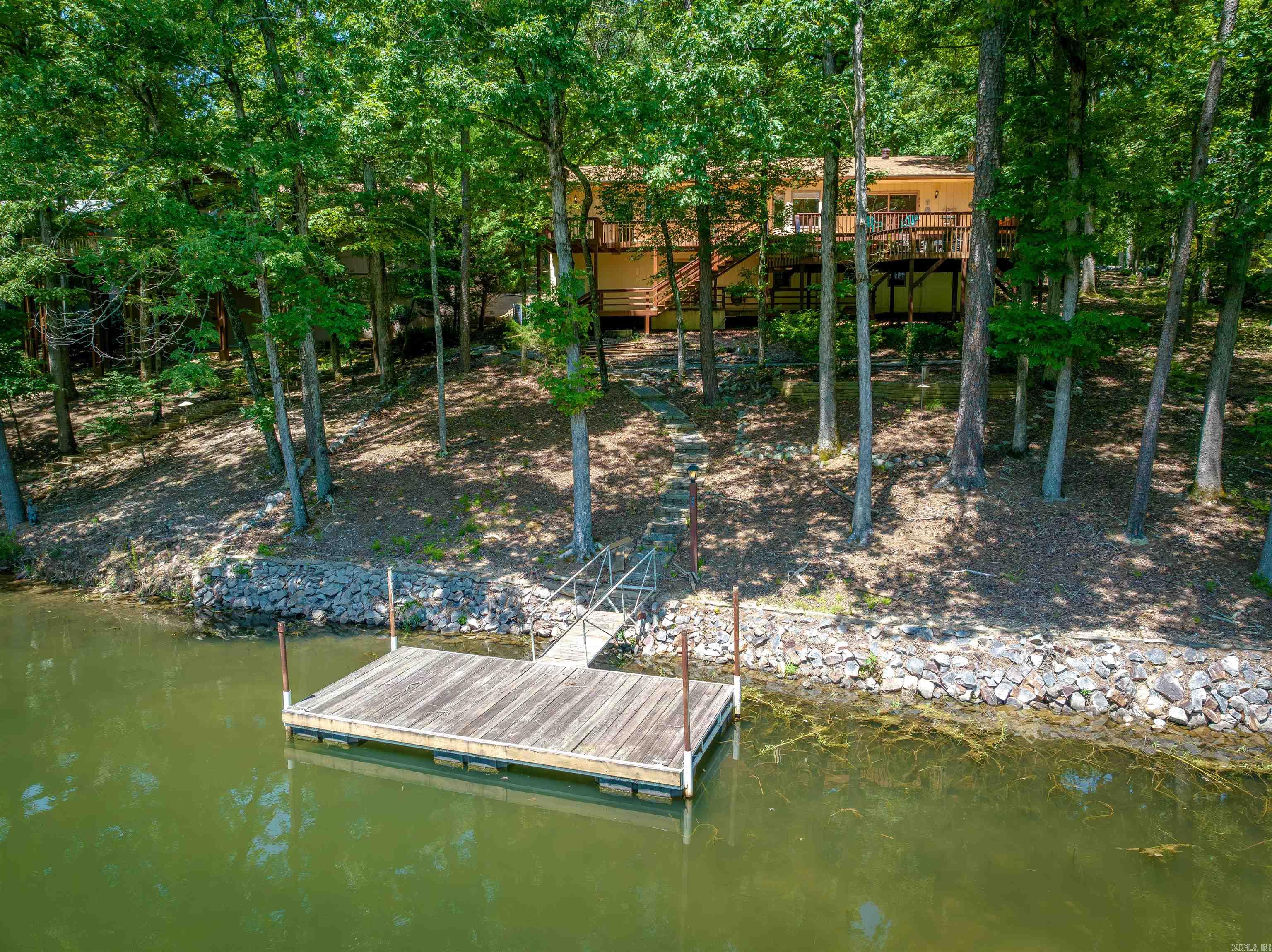 Lake Cortez WATERFRONT (full recreation lake - 240 acres) at an affordable price! 2Bedrooms/2Baths on the main floor and 1Bed/1Bath down + 500sq ft heated & cooled shop (NOT included in sq ft)! Enjoy sunrises AND the cool shade in summer afternoons with East-facing view over the water and your own swim dock! Quality solid wood flooring, tray and coved ceilings, stone fireplace, and a remodeled walk-in shower in the primary bathroom w/walk-in closet! Bright tile kitchen, remodeled hall bath, skylight, and eating area open to the 2-tier entertainment sized deck! Hot Springs Village is 26,000 gated acres with 11 lakes and 9 golf courses, tennis, pickleball, miniature golf, bocce ball, dog park, archery range, fitness center, indoor & outdoor pools, performing arts center, 20+ miles of trails, and much more!!!